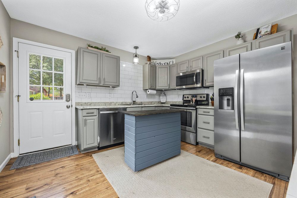 A kitchen with stainless steel appliances and a blue island.
