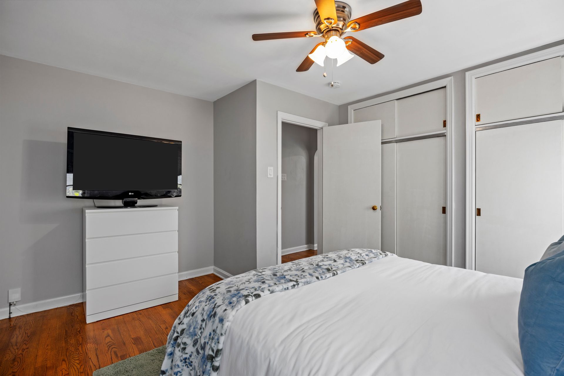 A bedroom with a bed , television and ceiling fan.
