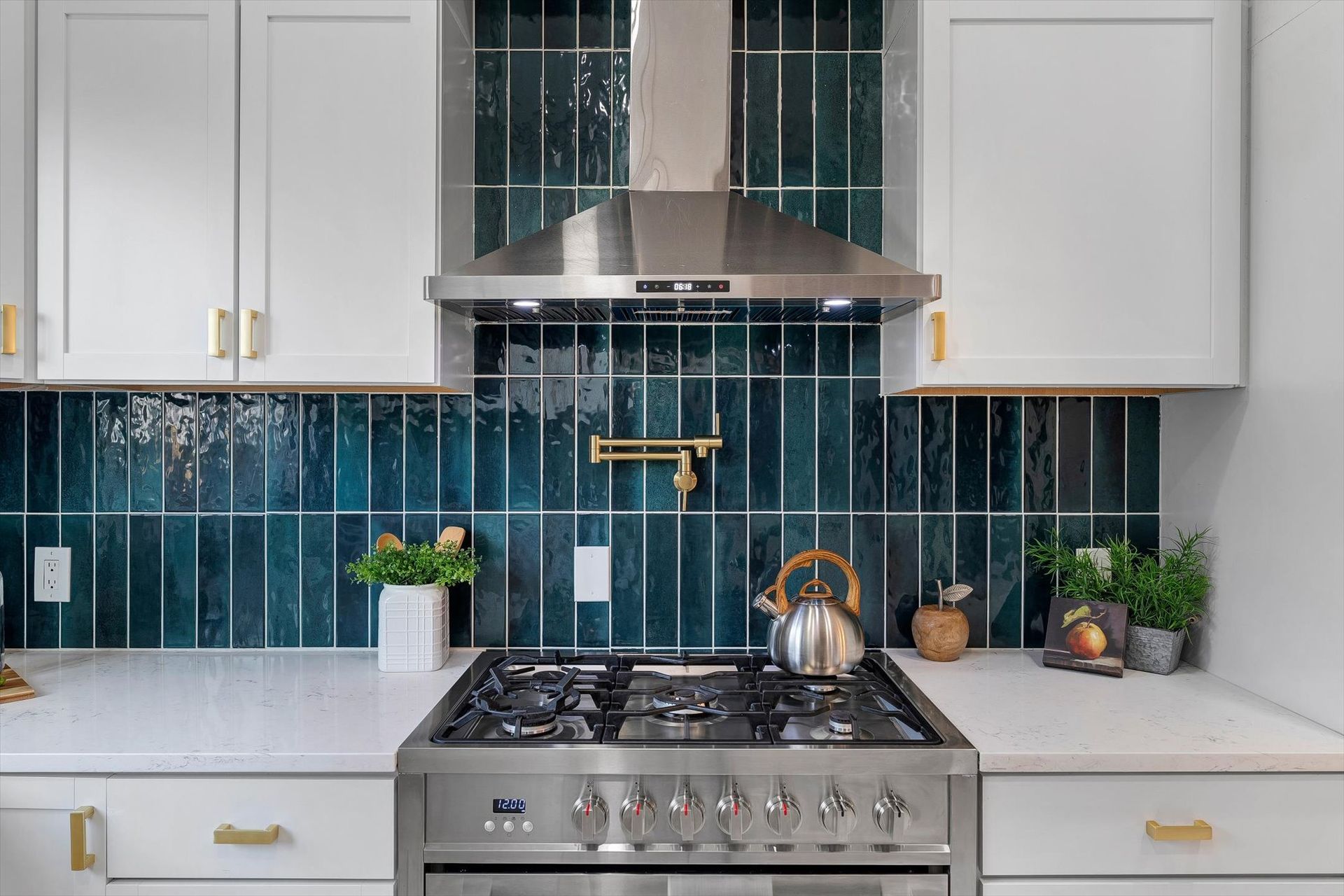 White kitchen with teal tile backsplash, stainless steel range, and white cabinets.