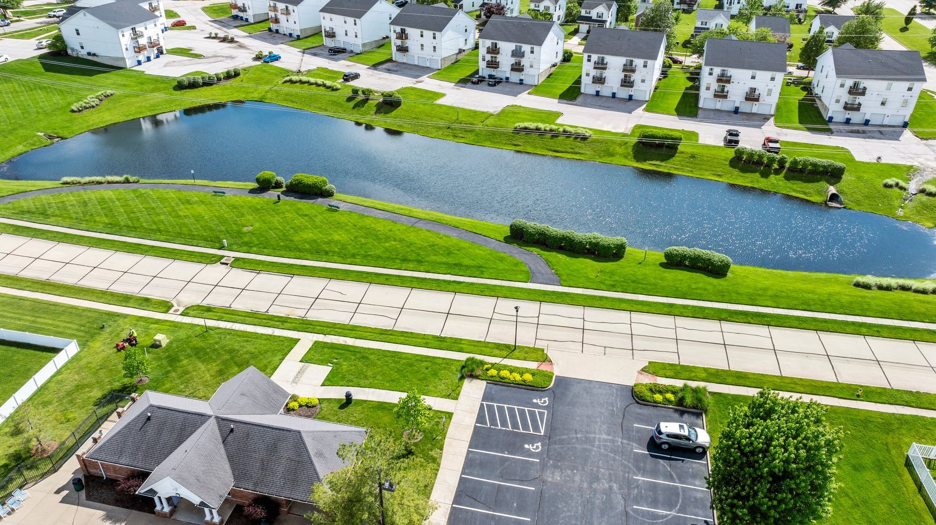 An aerial view of a residential area with a pond and houses.