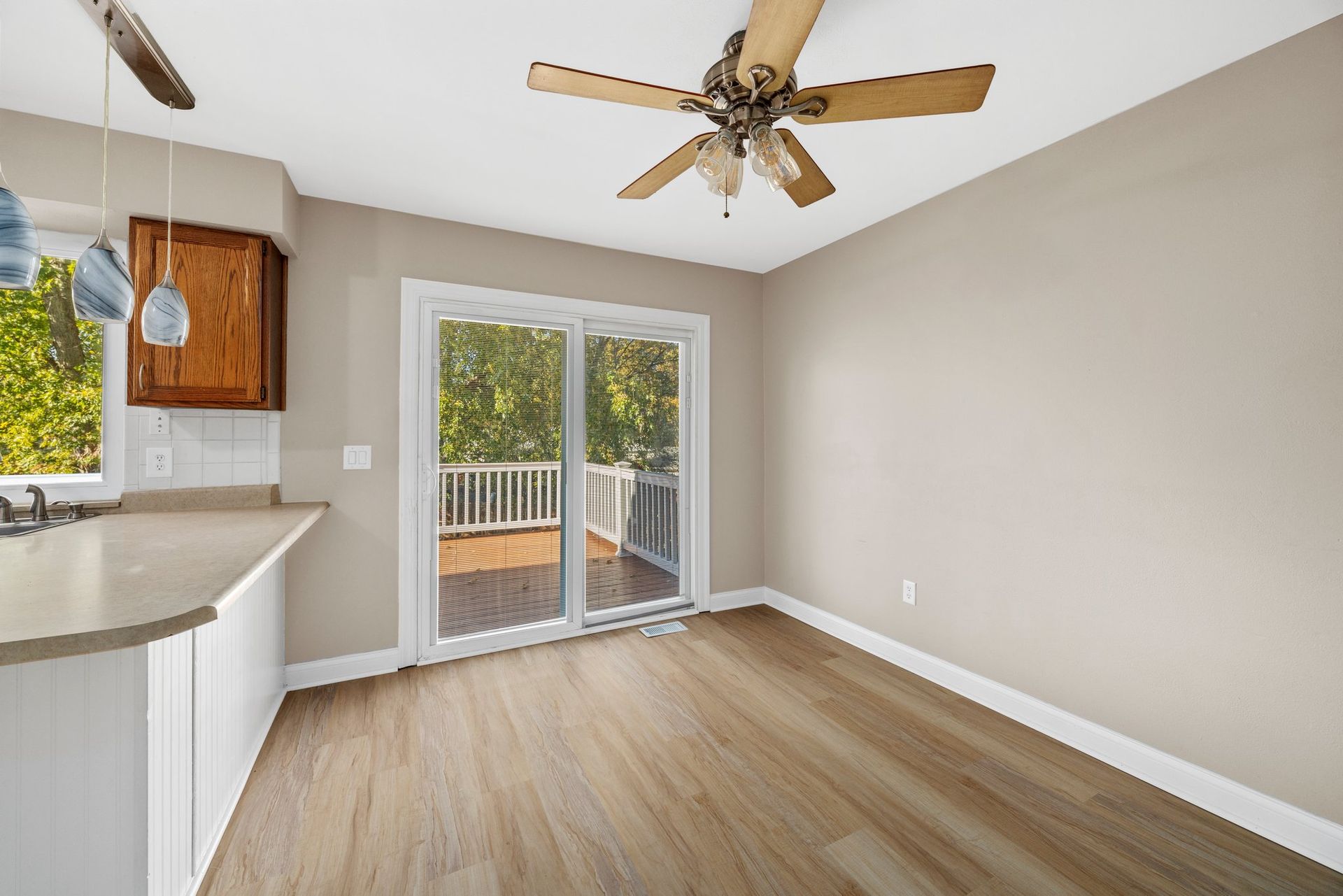 An empty room with a ceiling fan and sliding glass doors.