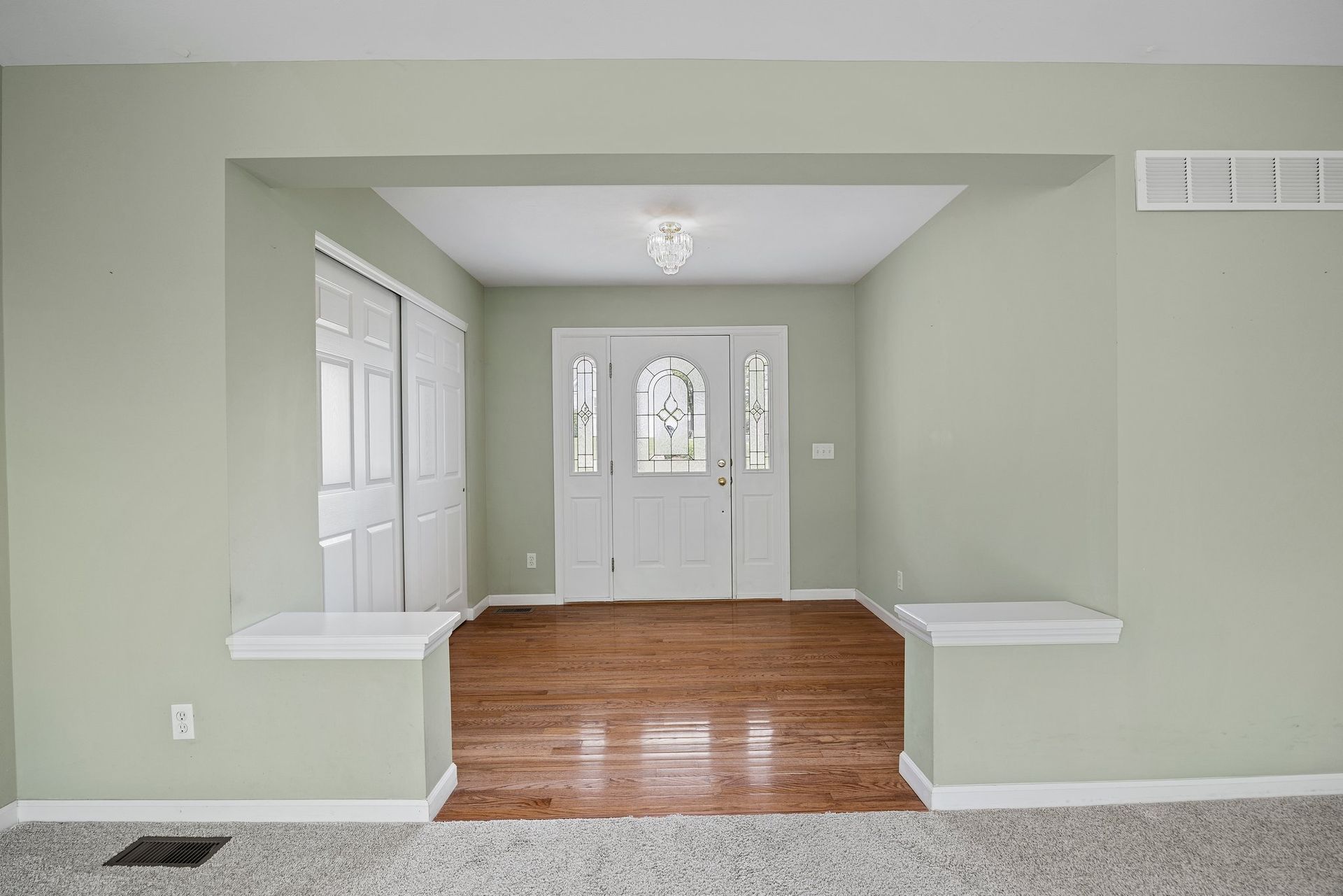 An empty living room with hardwood floors and a white door.