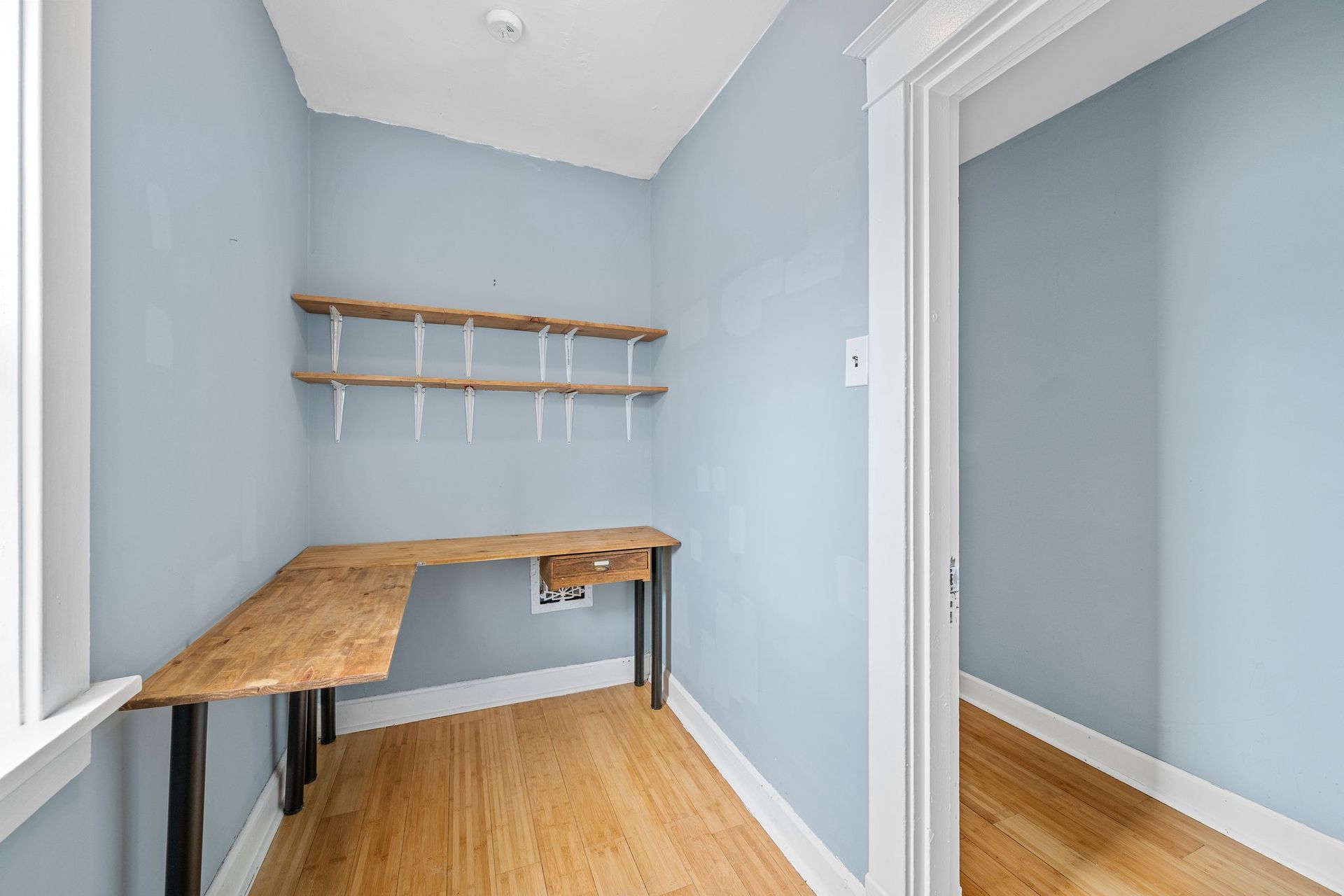An empty room with a wooden desk and shelves.