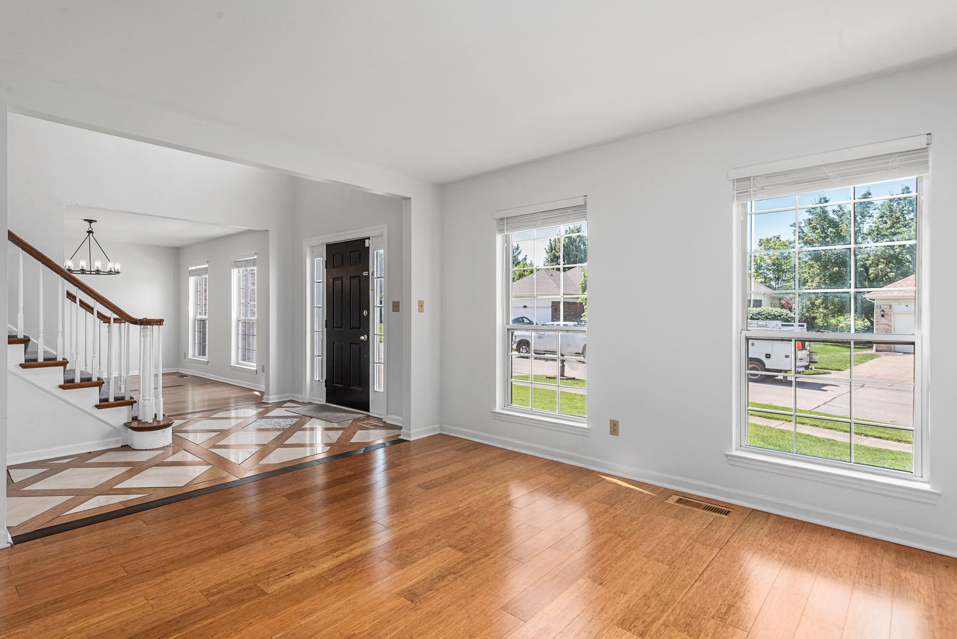 An empty living room with hardwood floors and white walls.