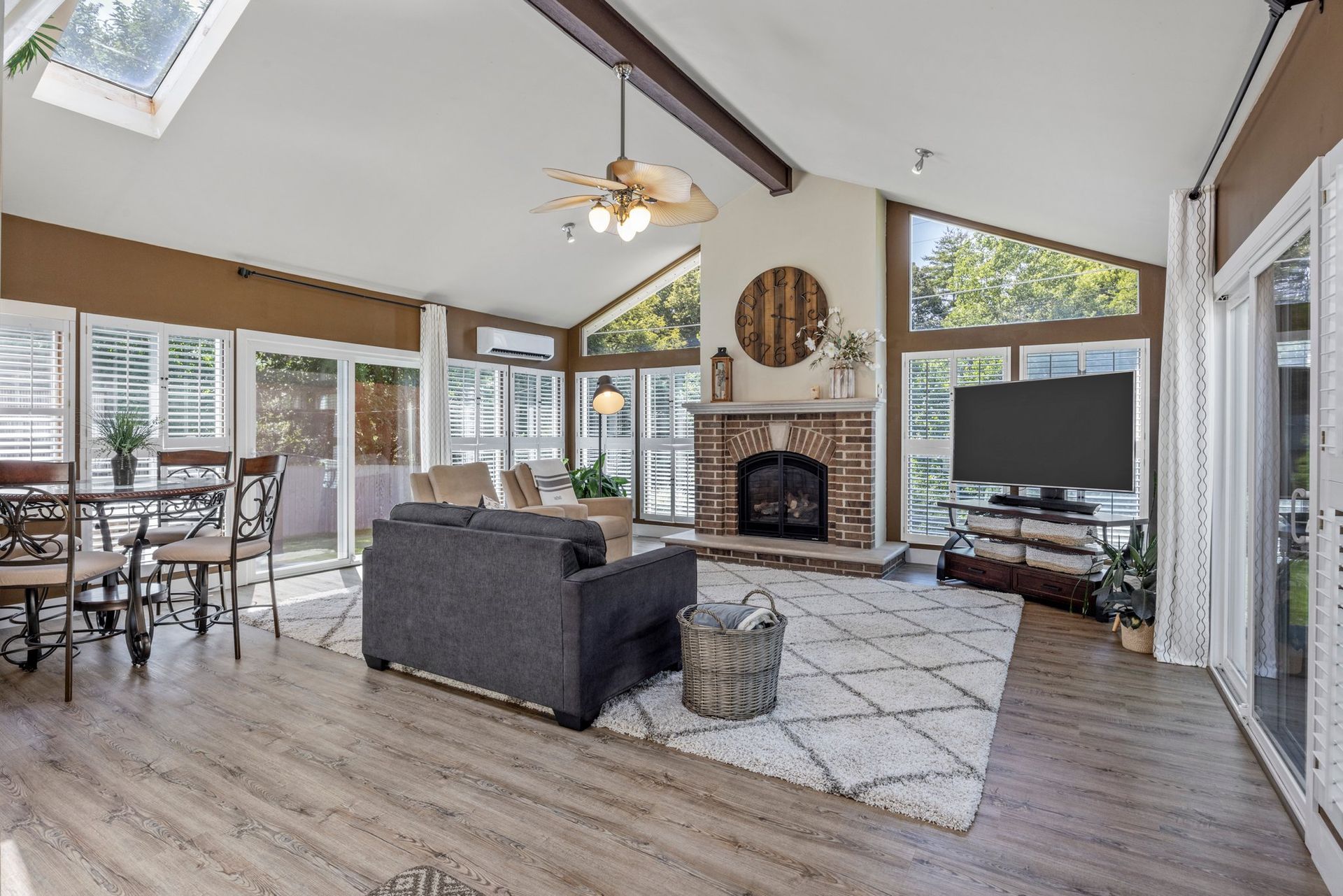 A living room with a couch , chair , television and fireplace.