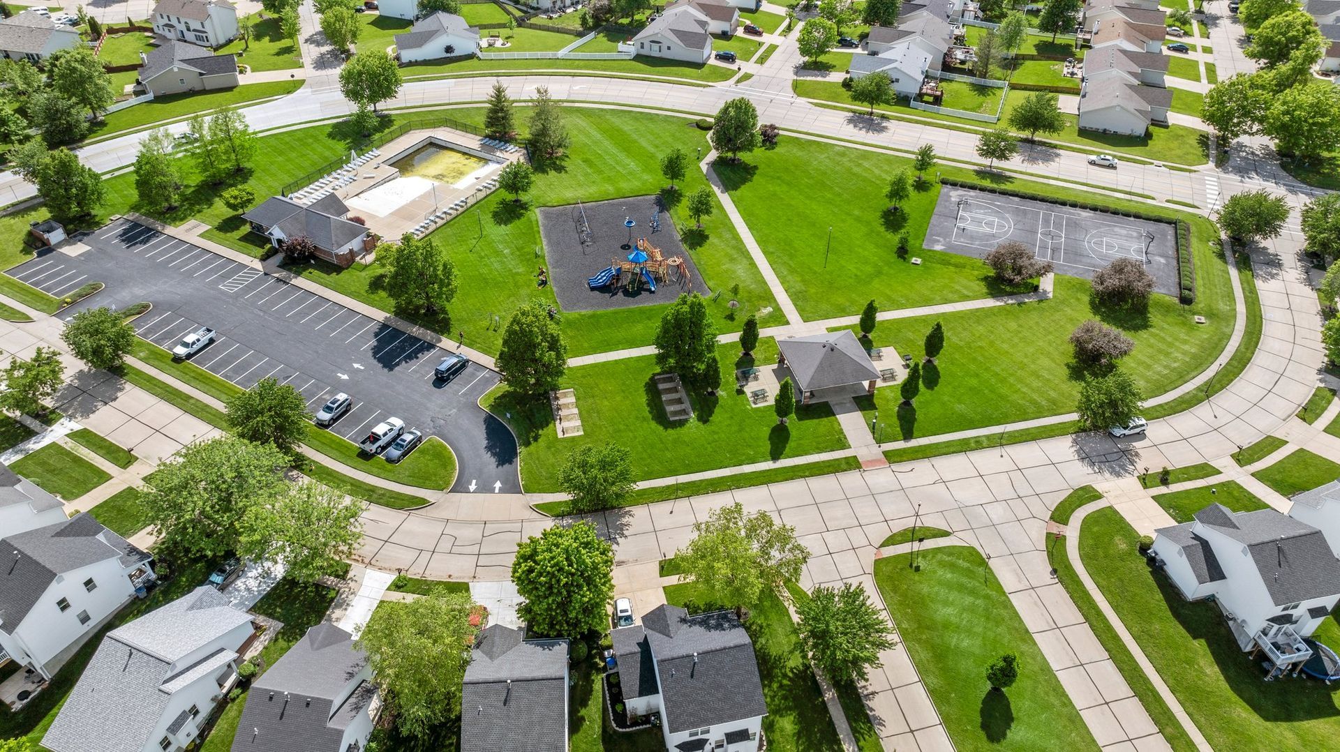 An aerial view of a residential neighborhood with a park in the middle.