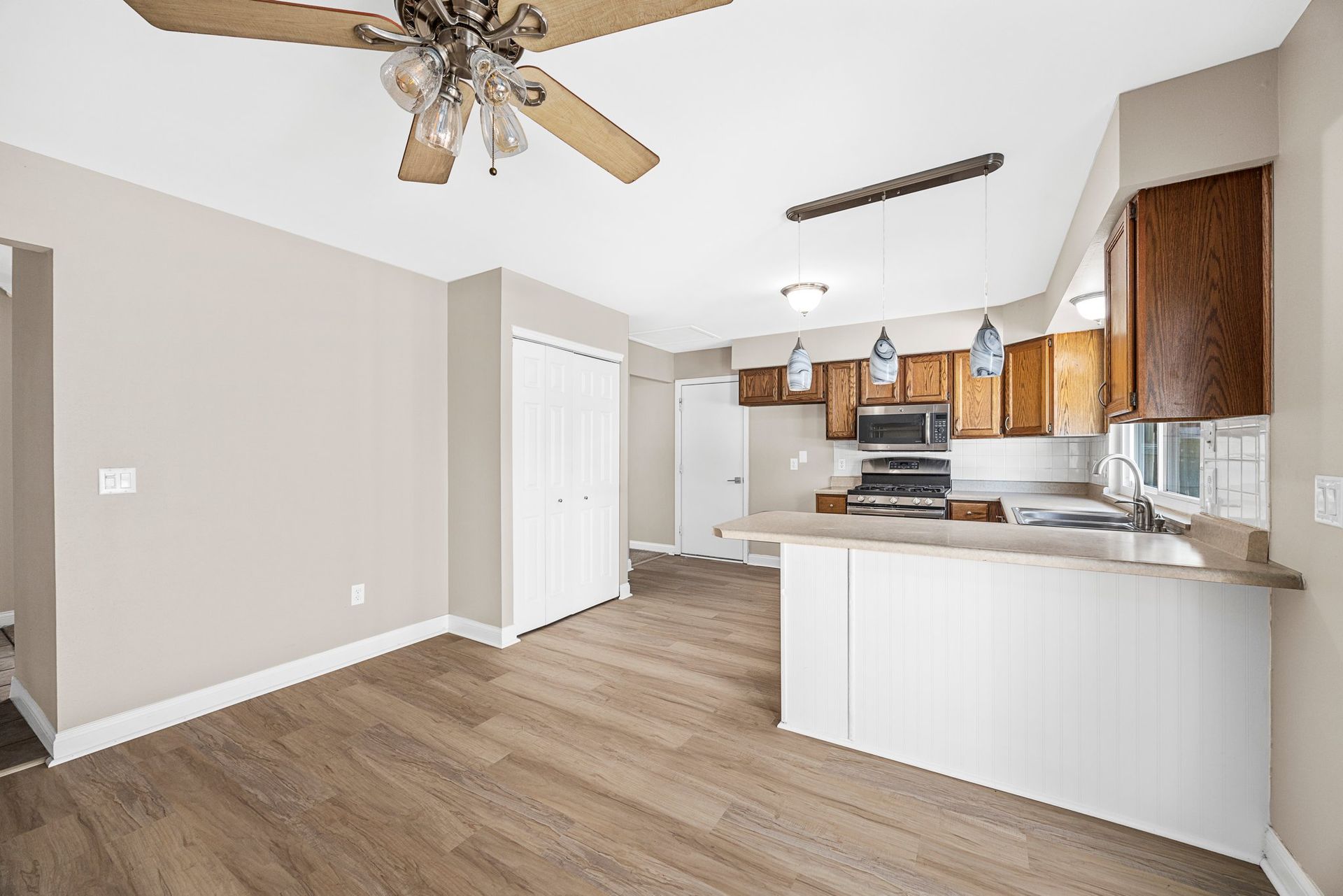 There is a ceiling fan in the living room and a kitchen.