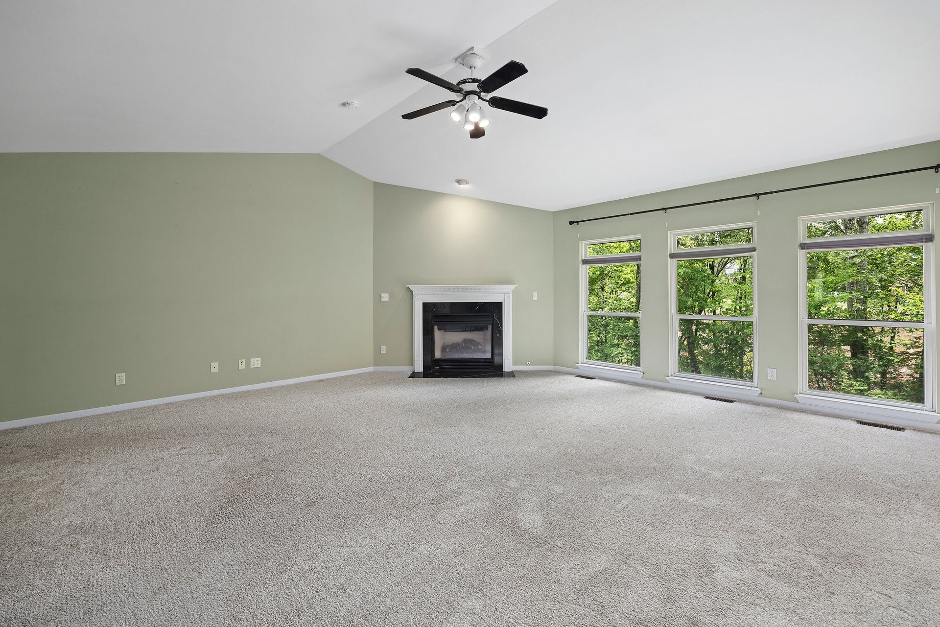 An empty living room with a fireplace and ceiling fan