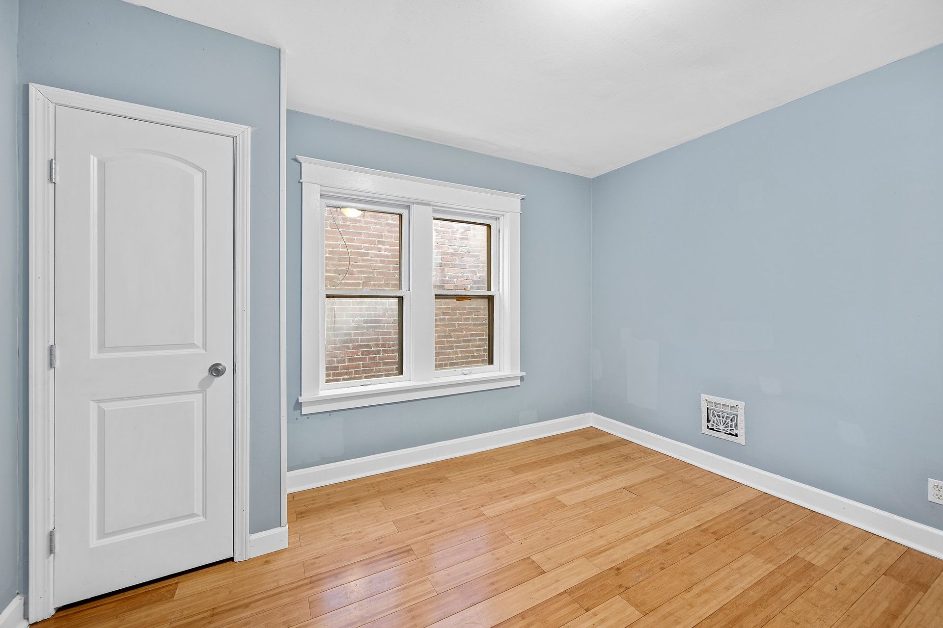 An empty bedroom with hardwood floors and blue walls.