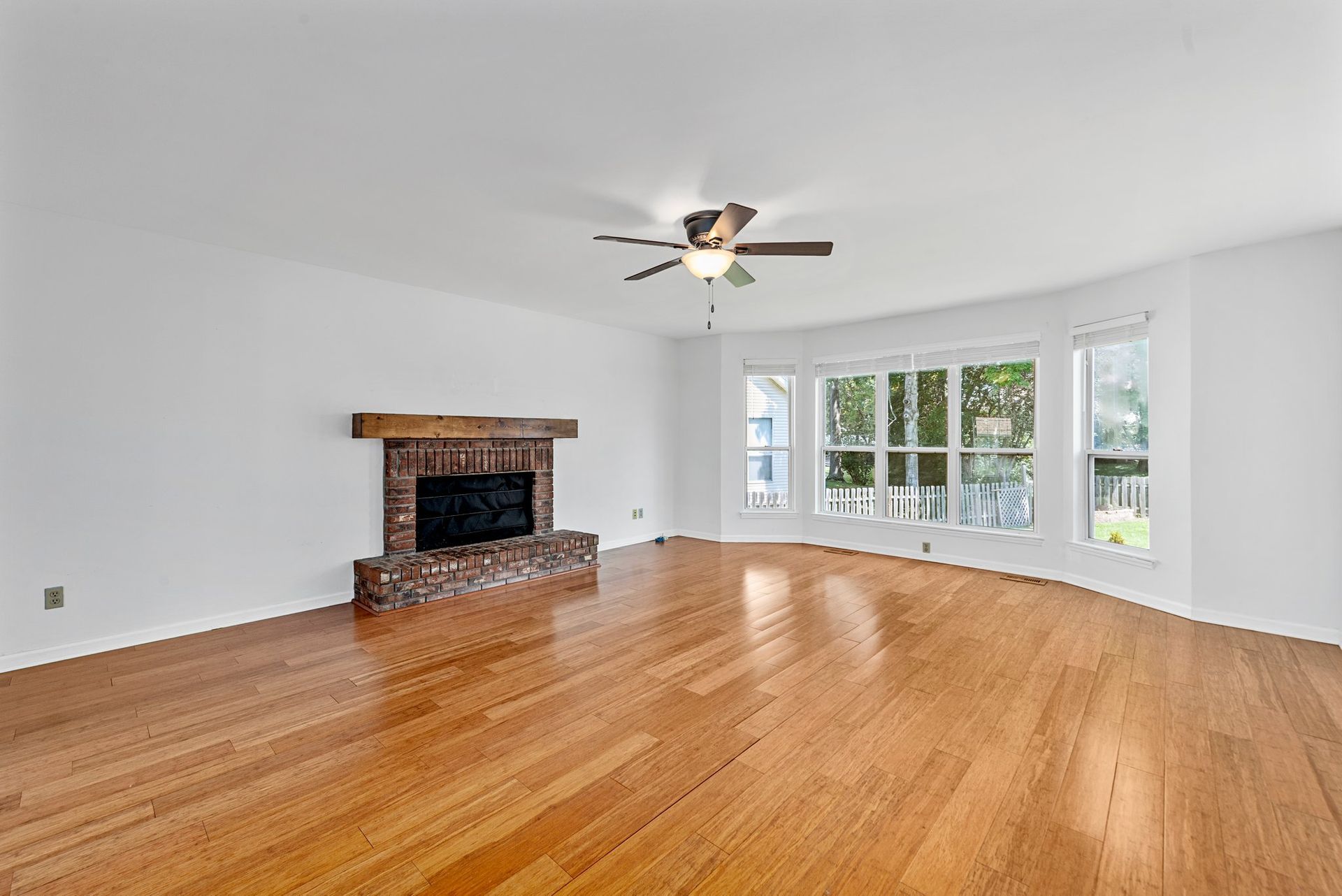 An empty living room with hardwood floors and a fireplace.