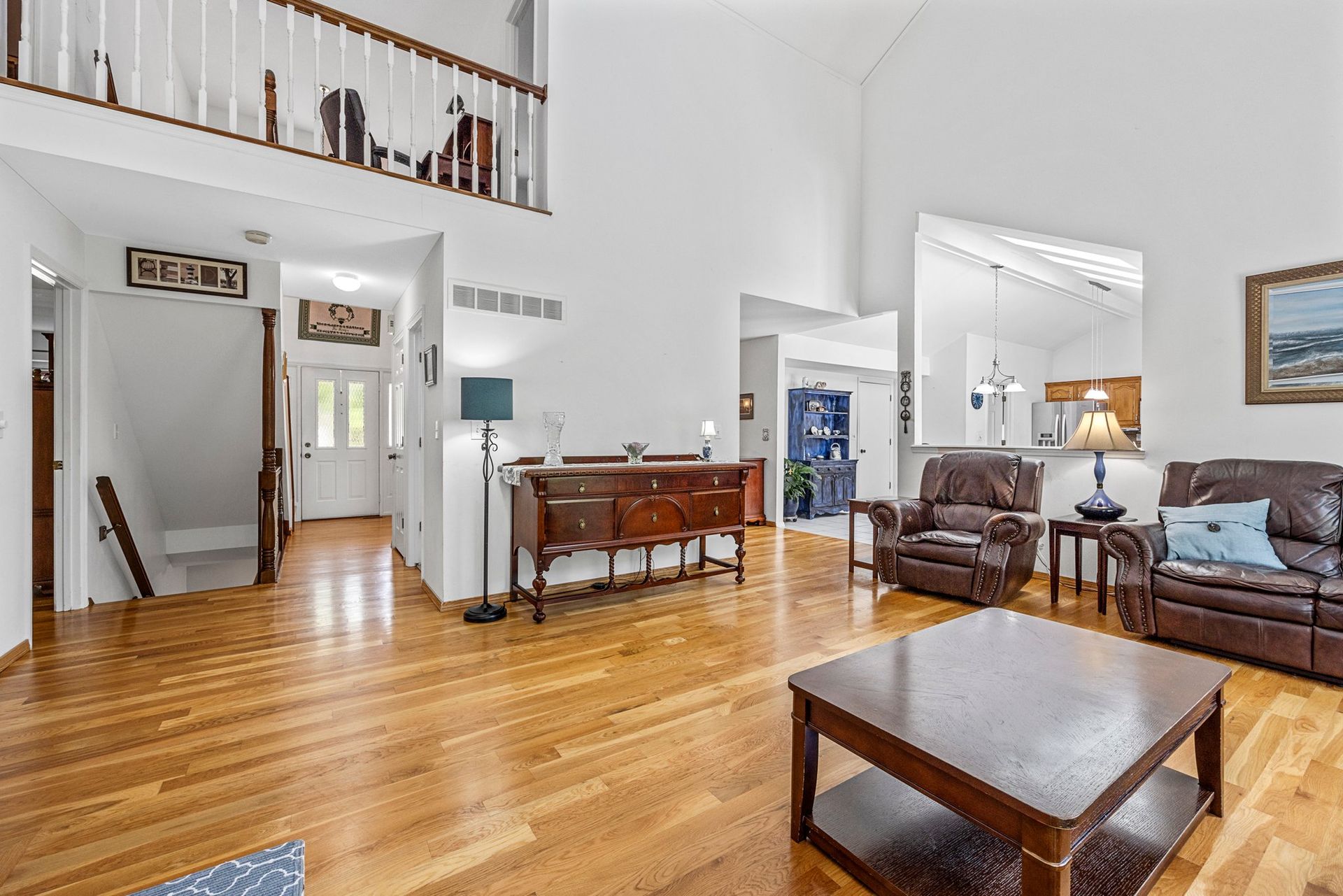 A living room with hardwood floors , a couch , chairs , and a coffee table.