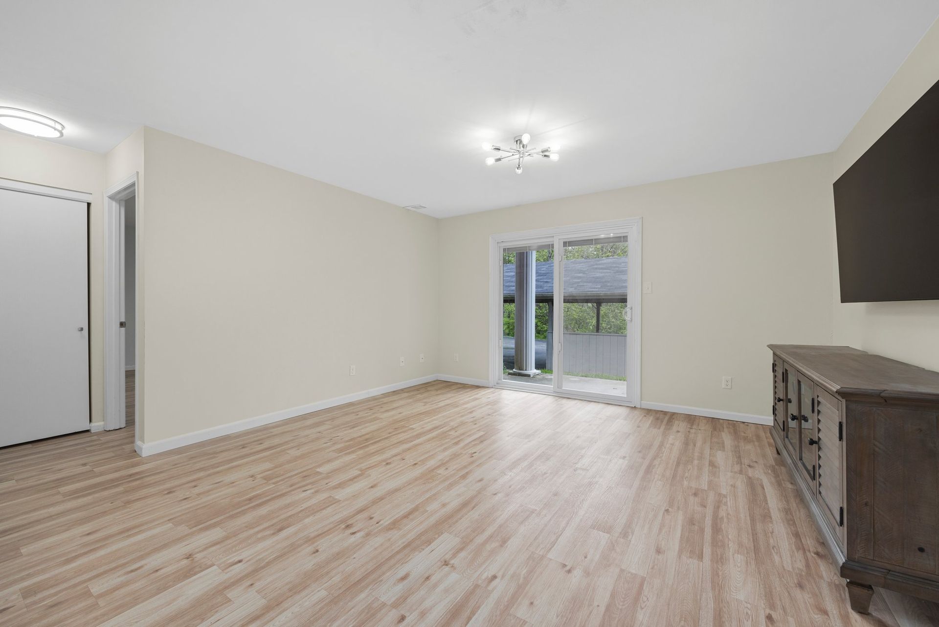 An empty living room with hardwood floors and a flat screen tv.