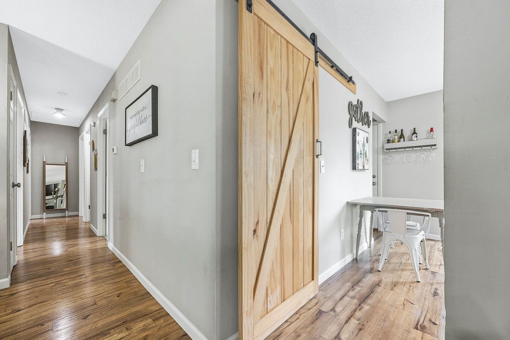 A hallway with a sliding barn door and hardwood floors
