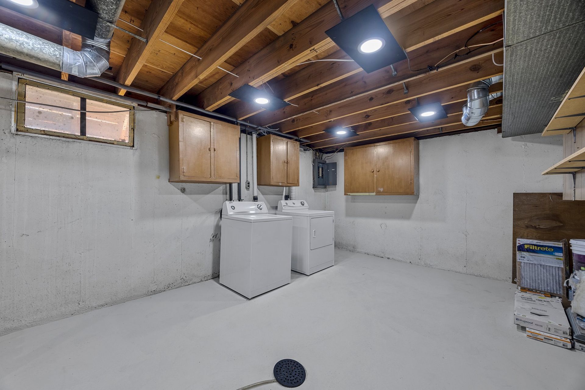 A basement laundry room with two washers and two dryers.