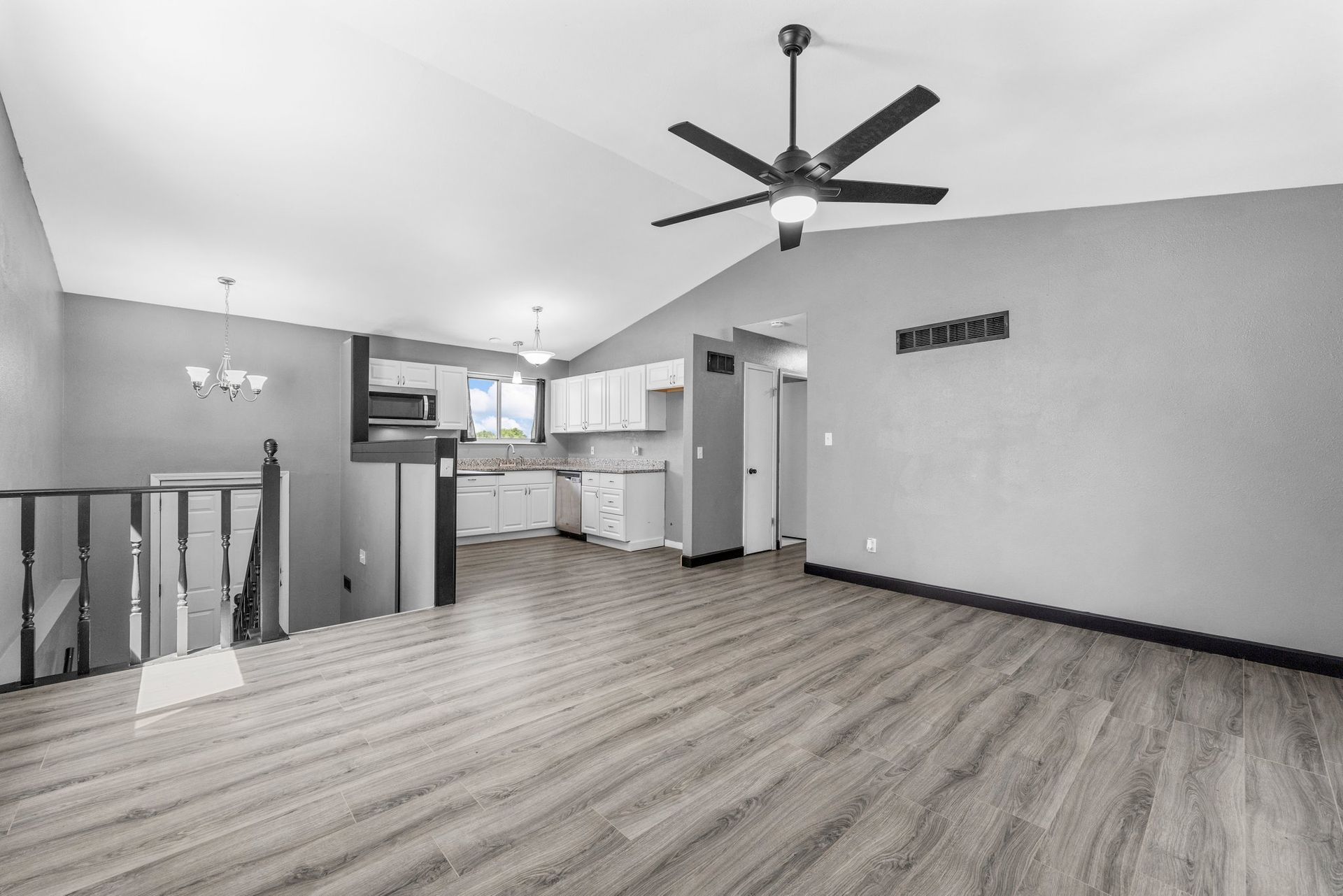 A black and white photo of an empty living room with a ceiling fan.