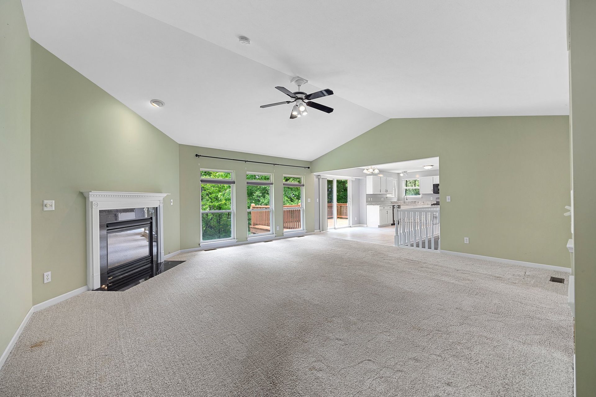 An empty living room with a fireplace and a ceiling fan.