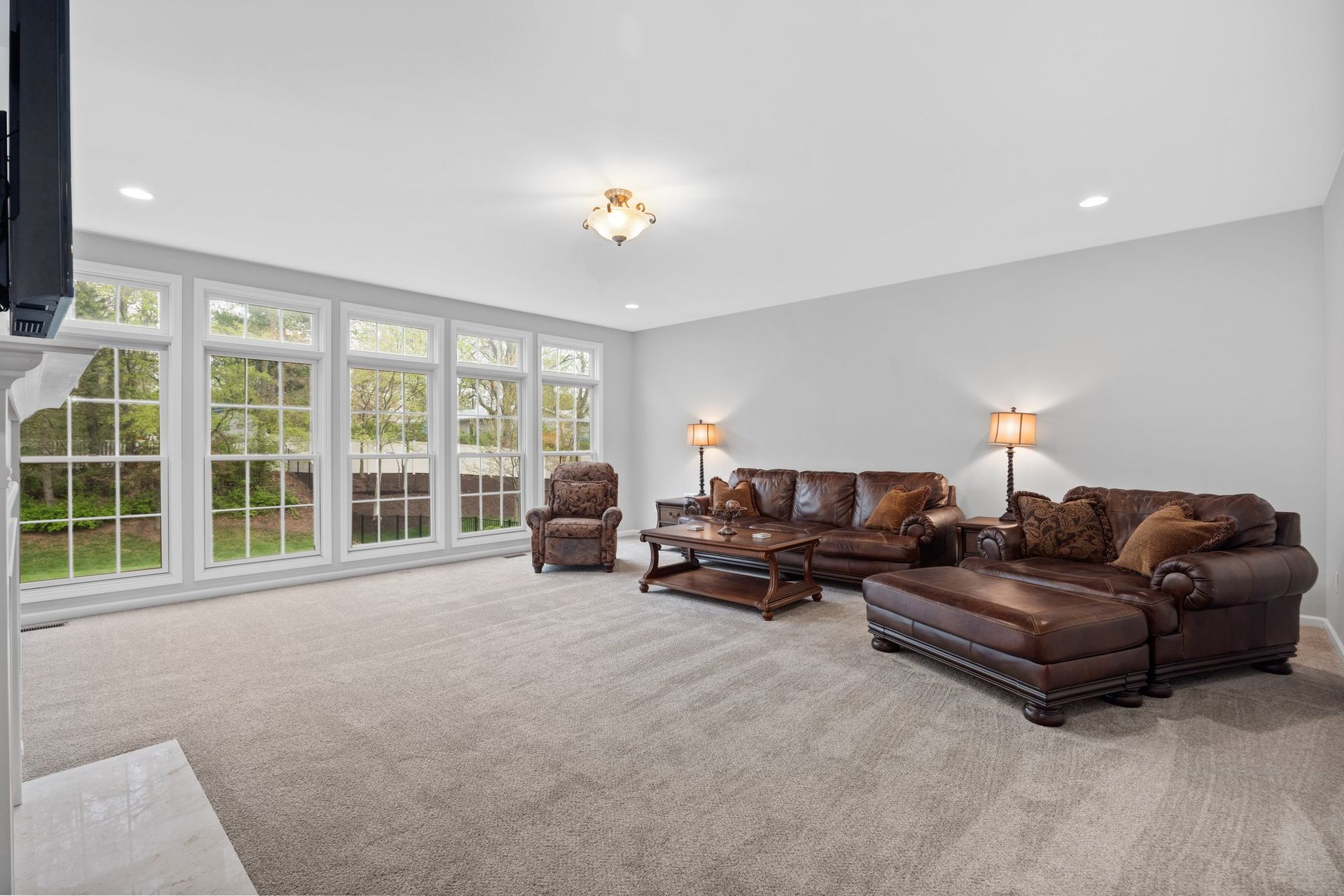 A living room with a couch , chairs , coffee table and television.