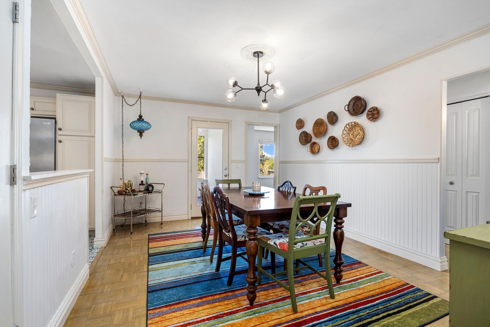 Dining room with dark wood table, colorful rug, and decorative wall plates.