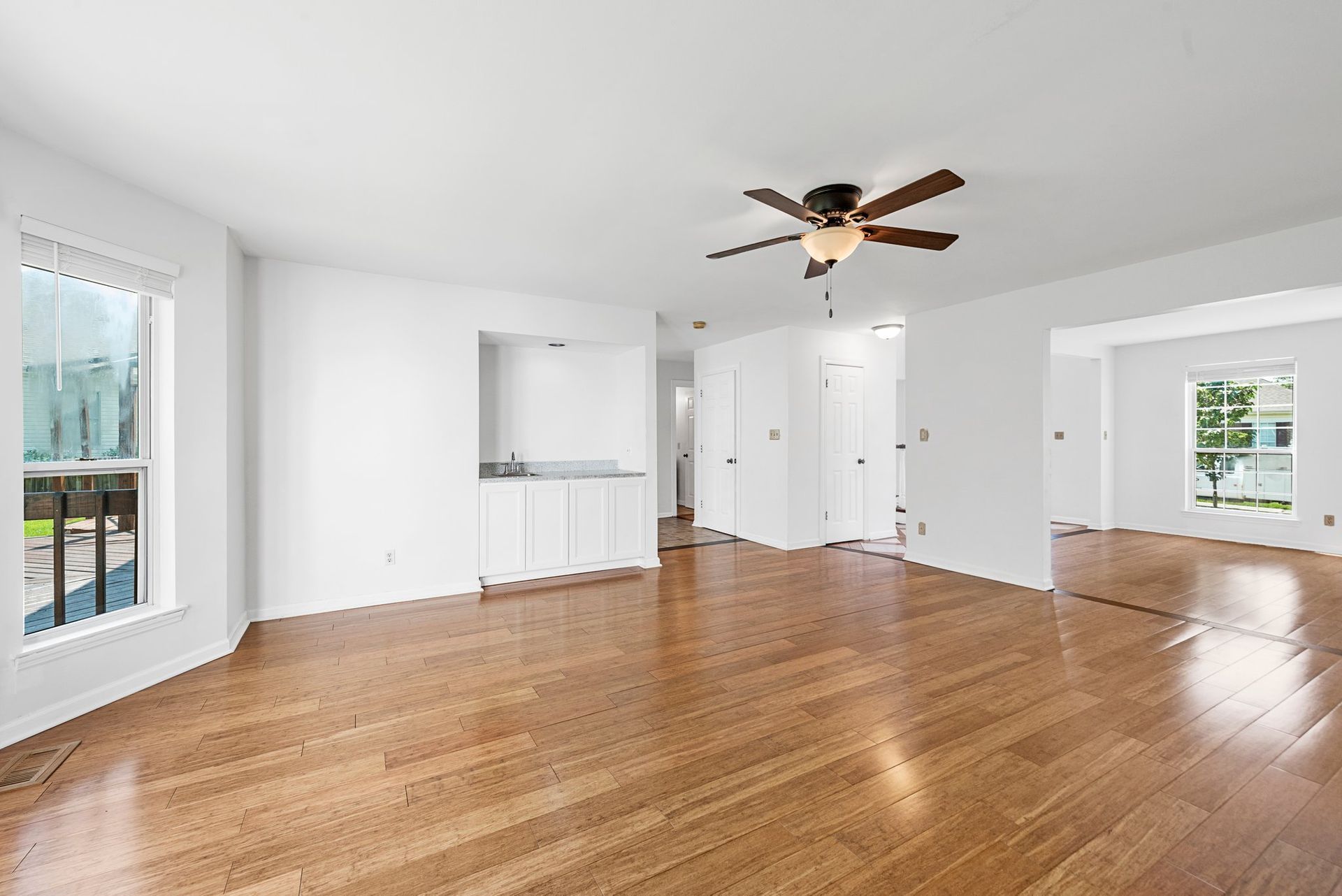 An empty living room with hardwood floors and a ceiling fan