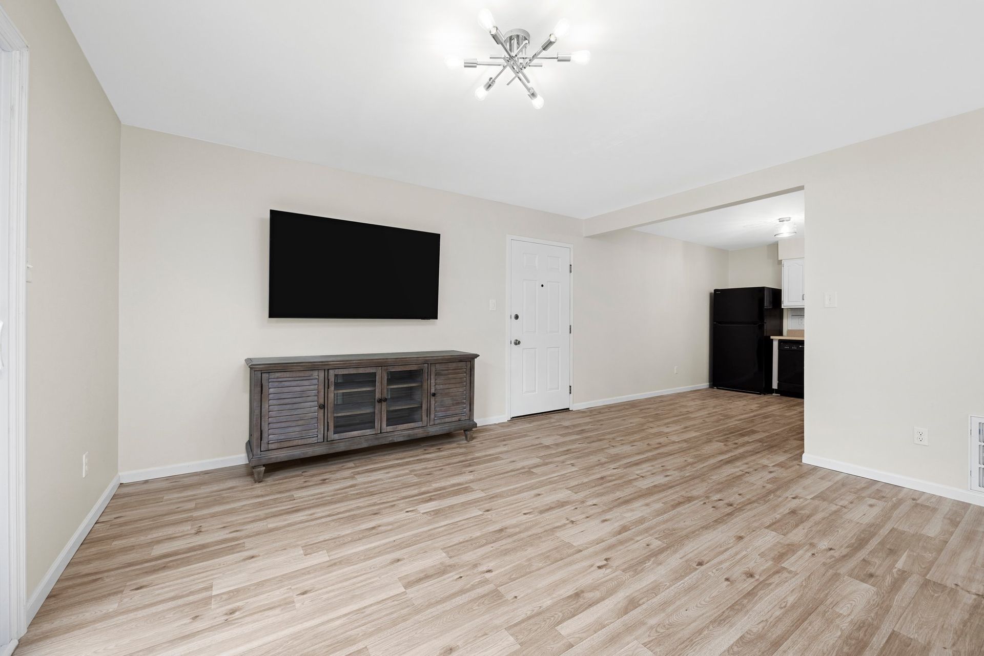A living room with hardwood floors and a flat screen tv on the wall.