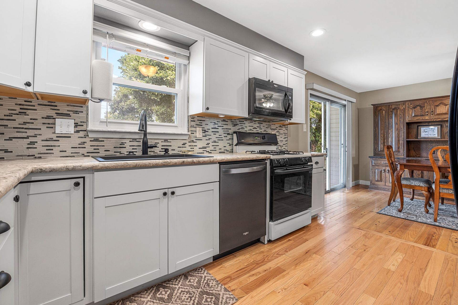 A kitchen with white cabinets , stainless steel appliances , and hardwood floors.