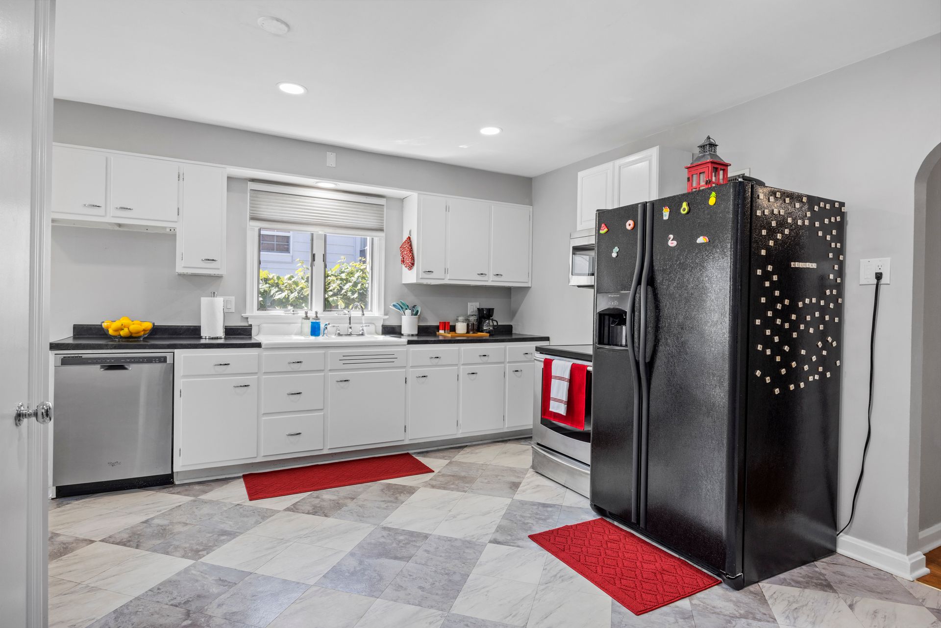 A kitchen with white cabinets and a black refrigerator.