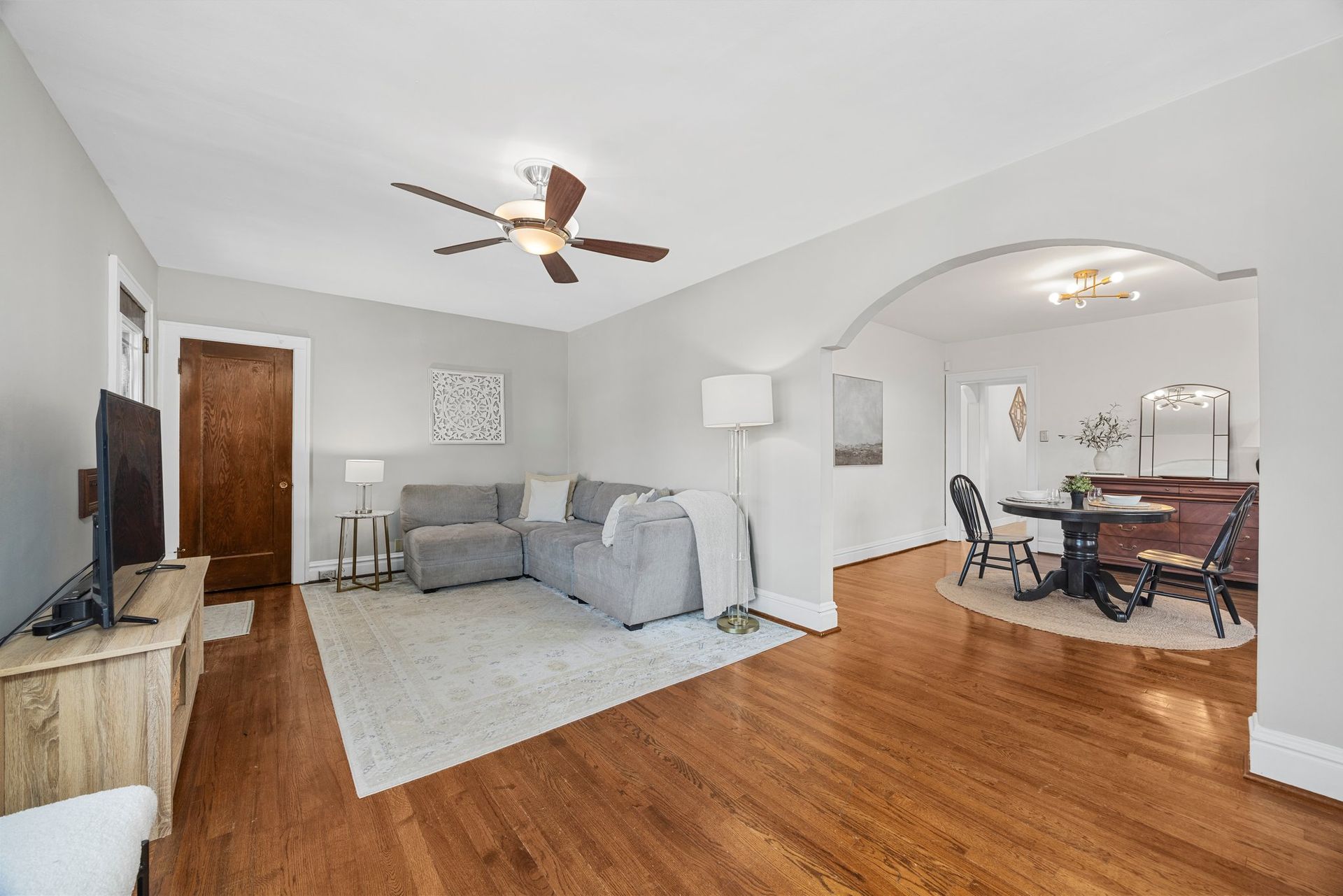 A living room with hardwood floors and a ceiling fan.