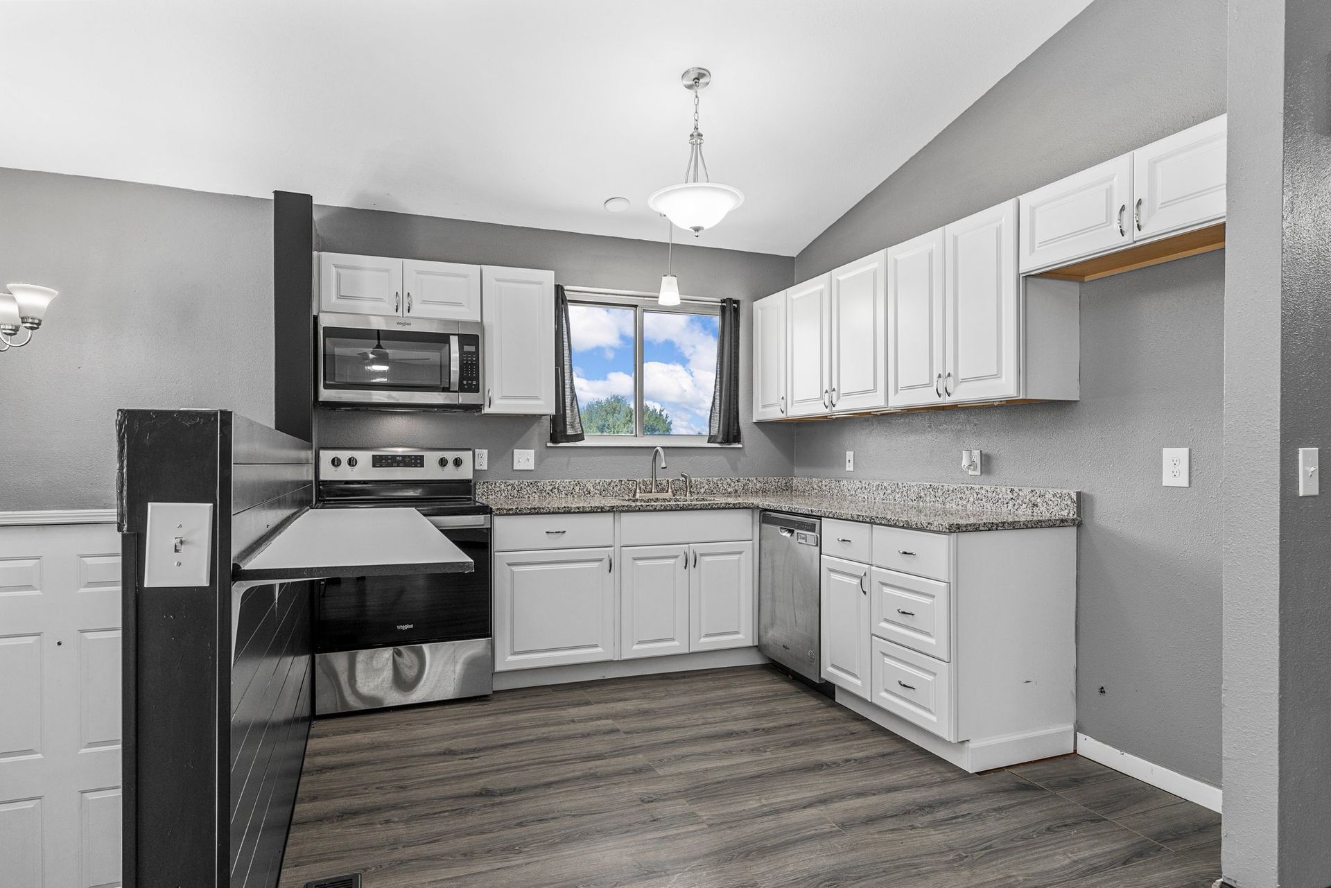 A kitchen with white cabinets , stainless steel appliances , and hardwood floors.