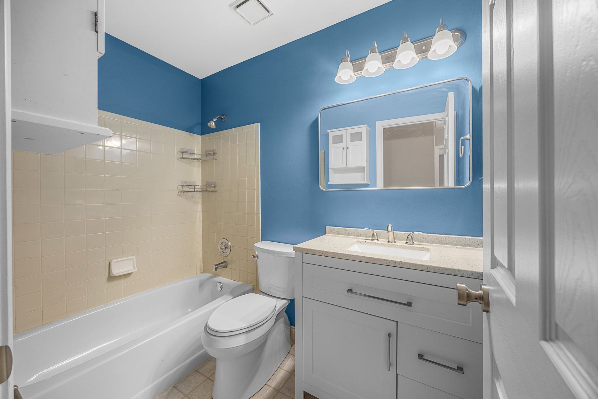 A bathroom with a toilet , sink , tub and mirror.