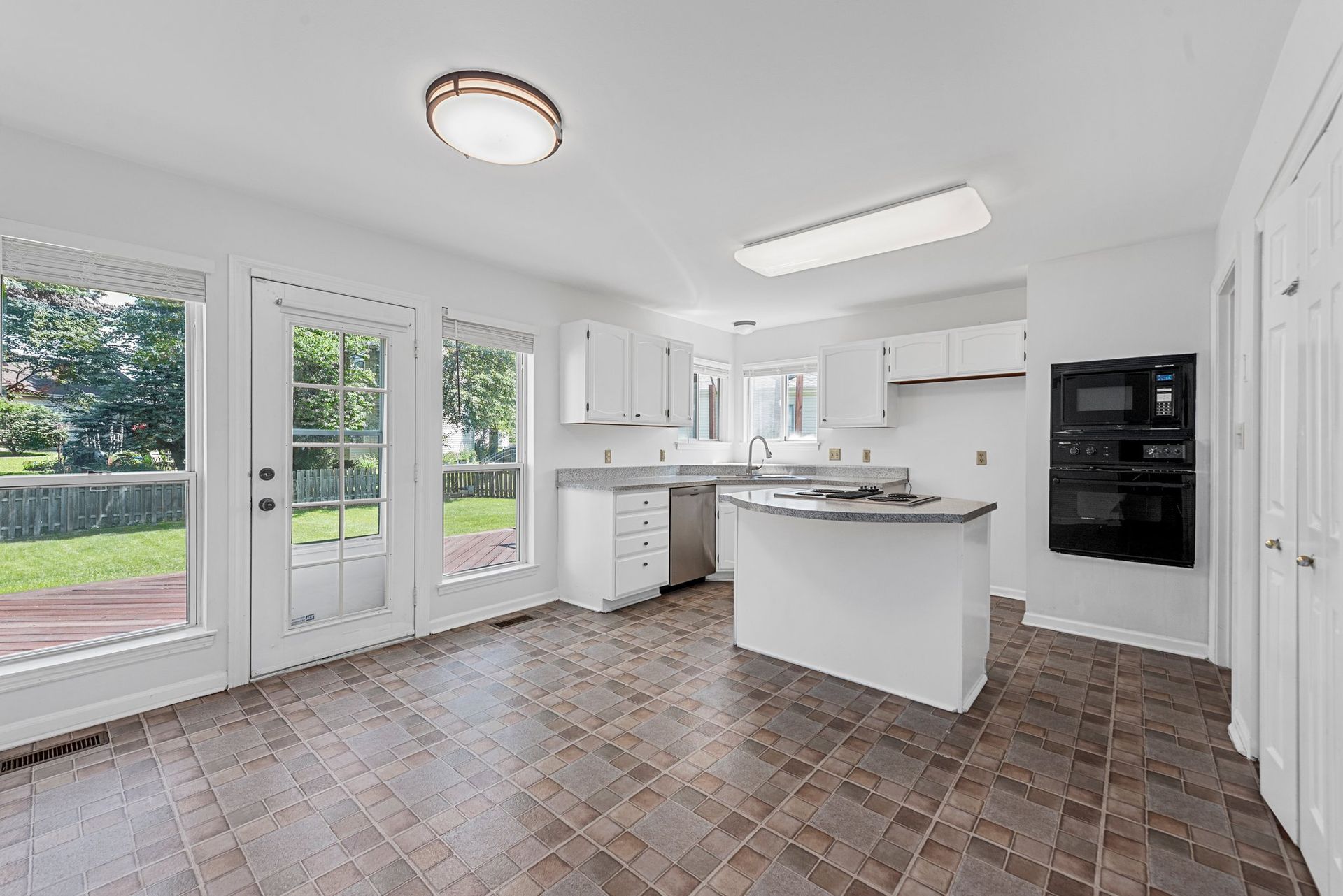 A kitchen with white cabinets , stainless steel appliances , and a large island.