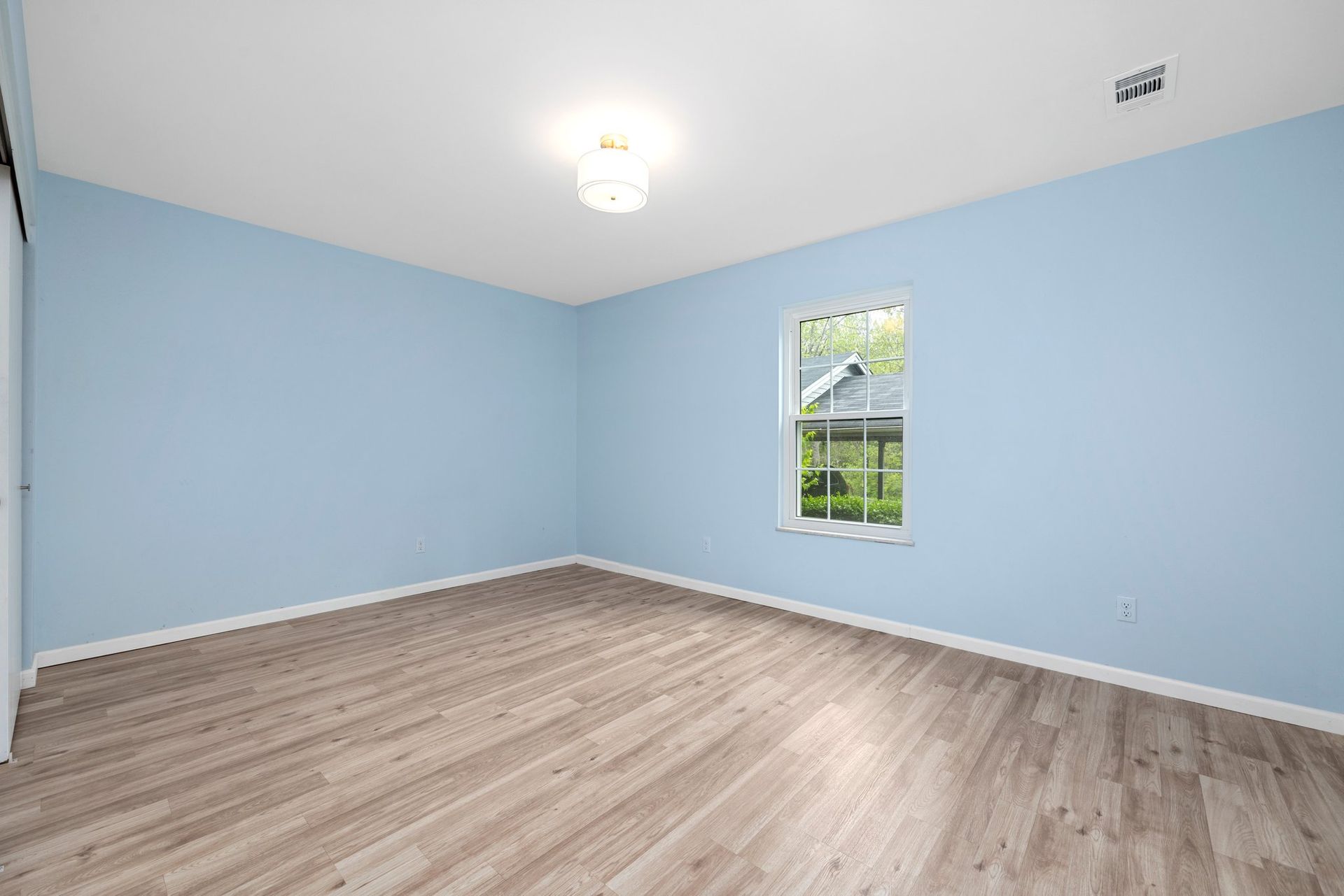 An empty room with blue walls and a window.