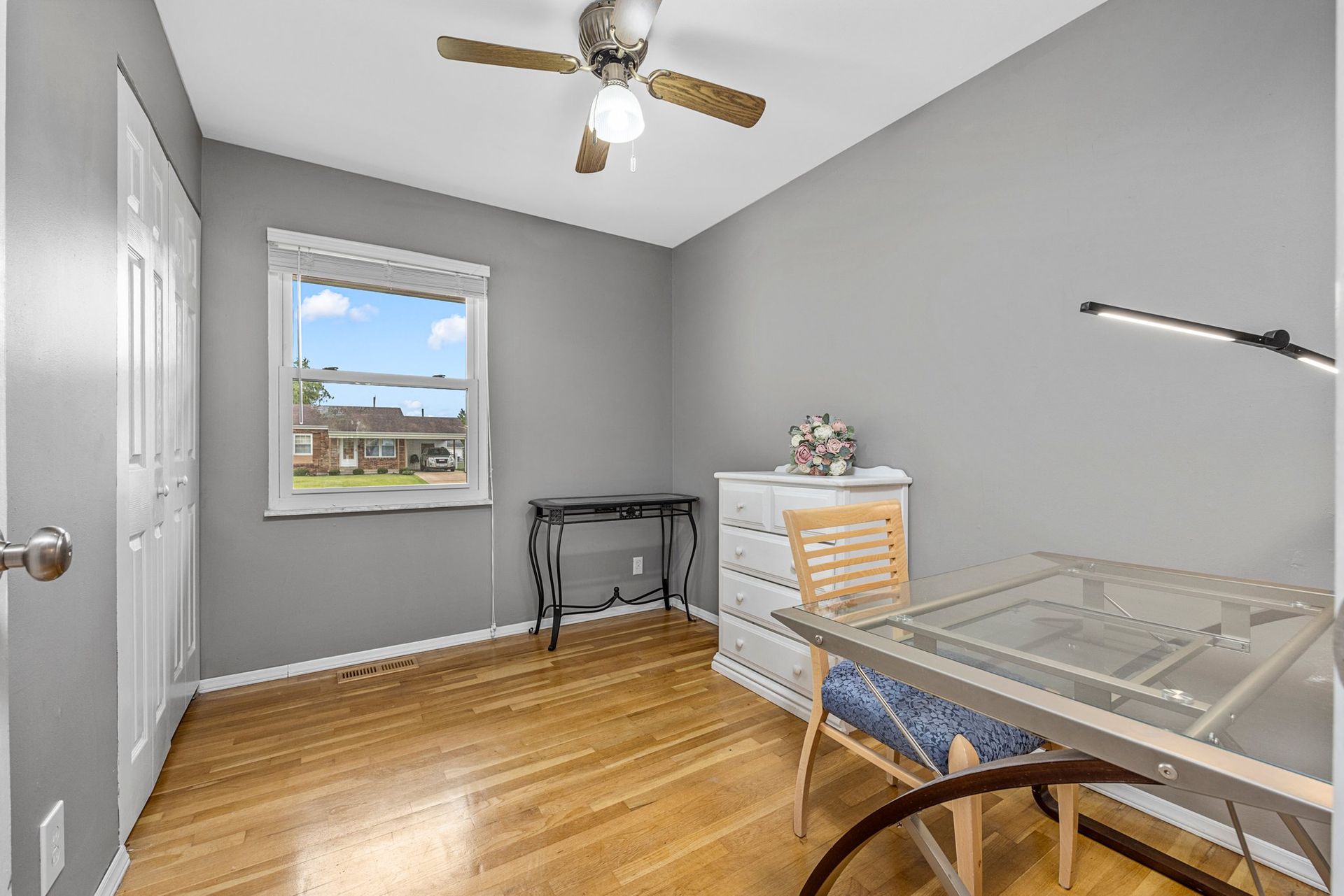 There is a ceiling fan in the room with a desk and chairs.