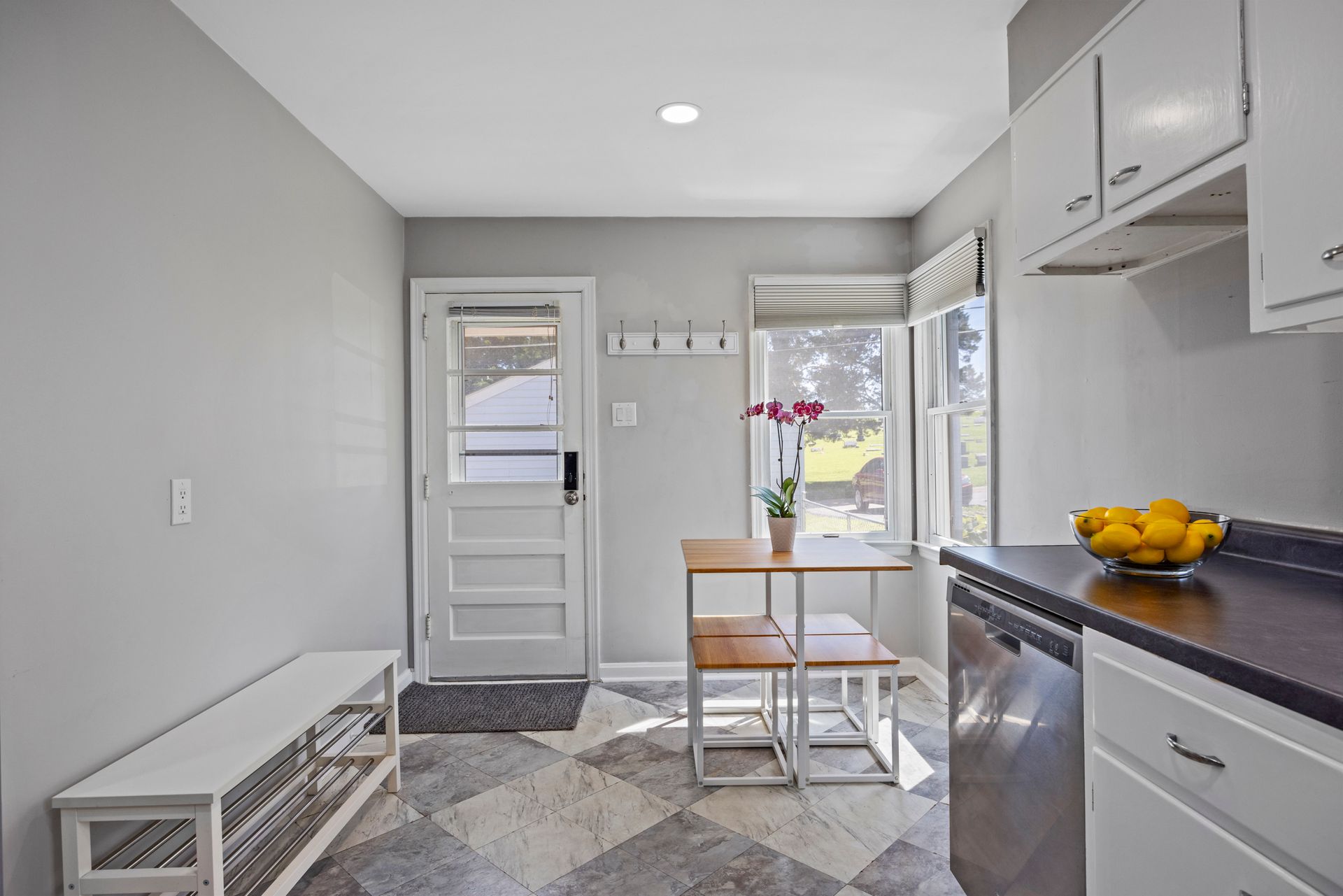 A kitchen with a table and chairs and a bowl of lemons on the counter.