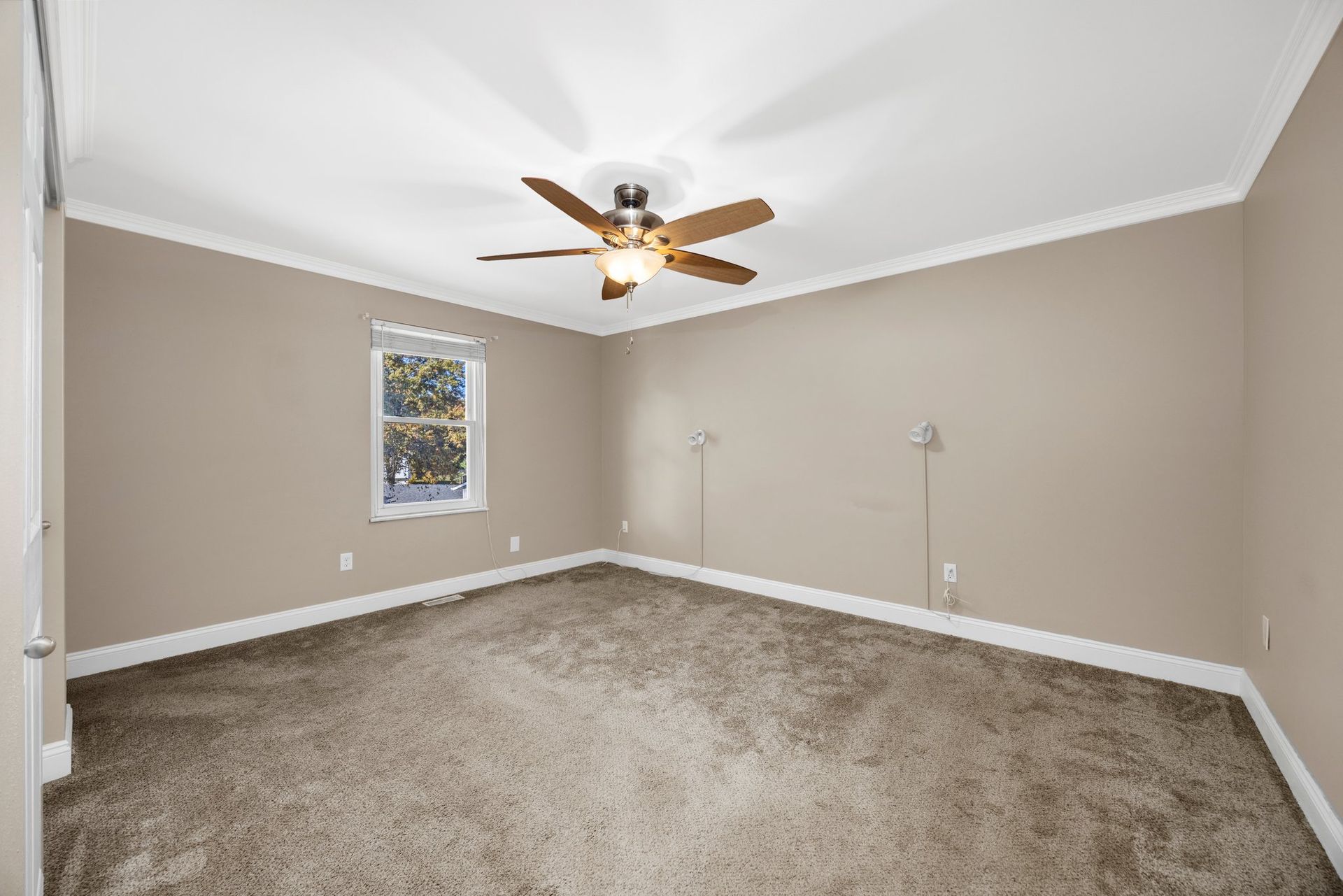 An empty bedroom with a ceiling fan and a window.