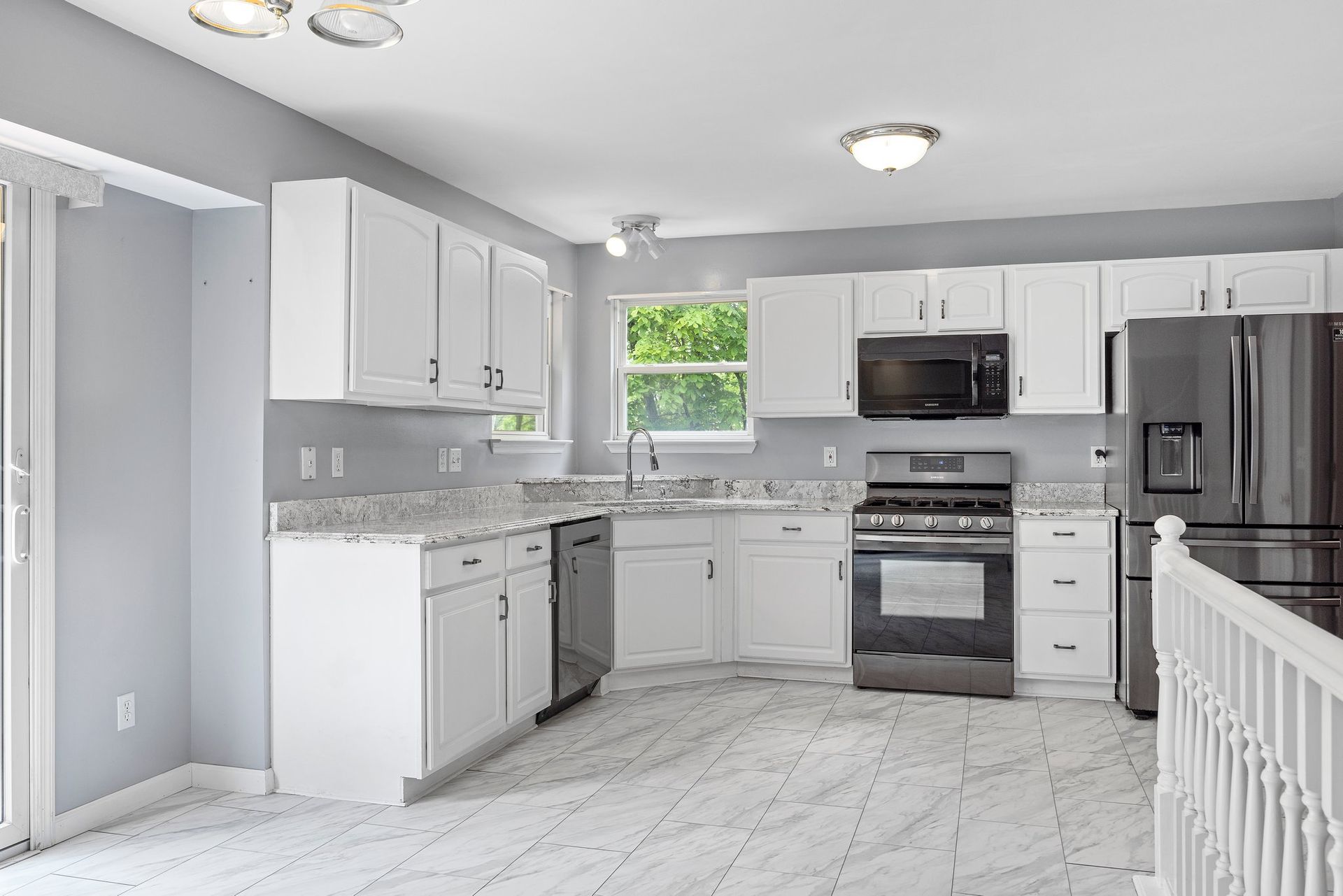An empty kitchen with white cabinets and stainless steel appliances.