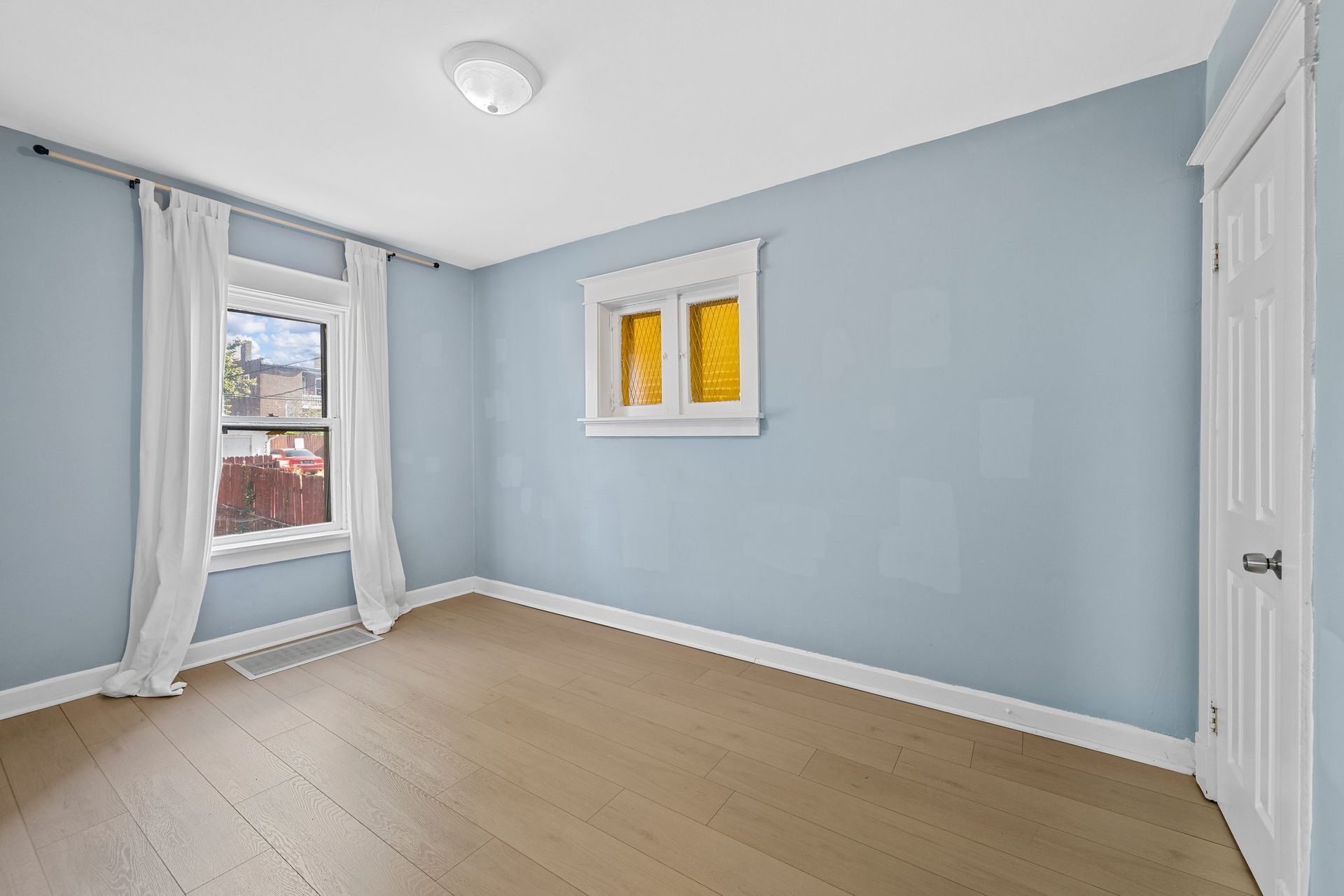 An empty room with blue walls and a window.