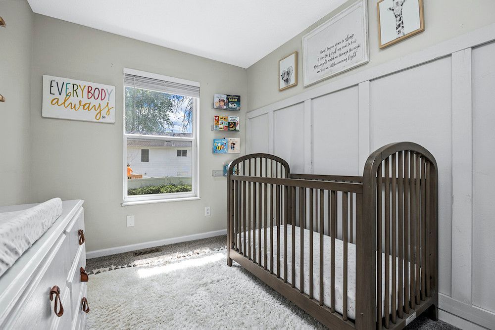 A baby room with a crib , dresser , and window.