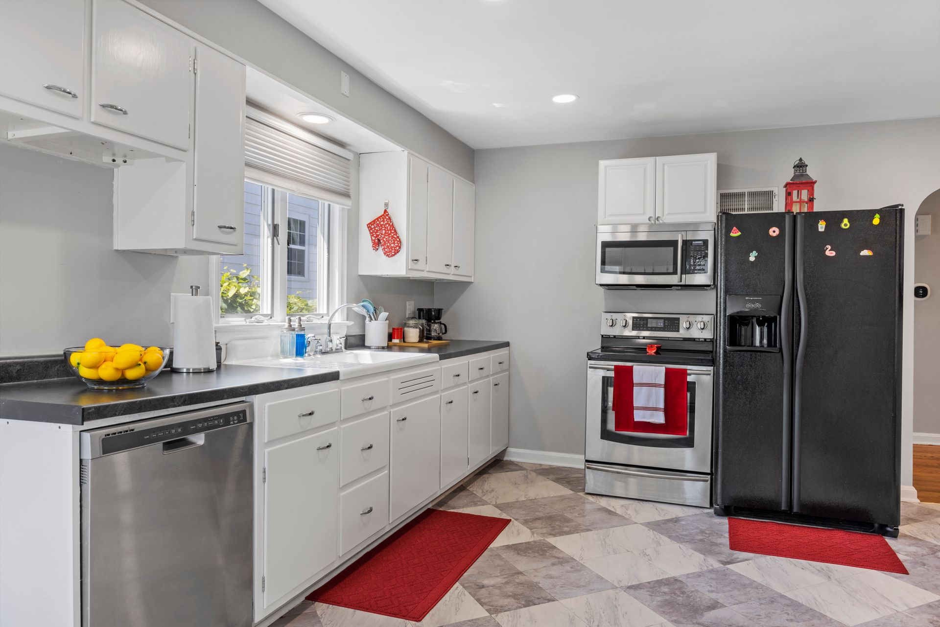 A kitchen with white cabinets , stainless steel appliances and a black refrigerator.