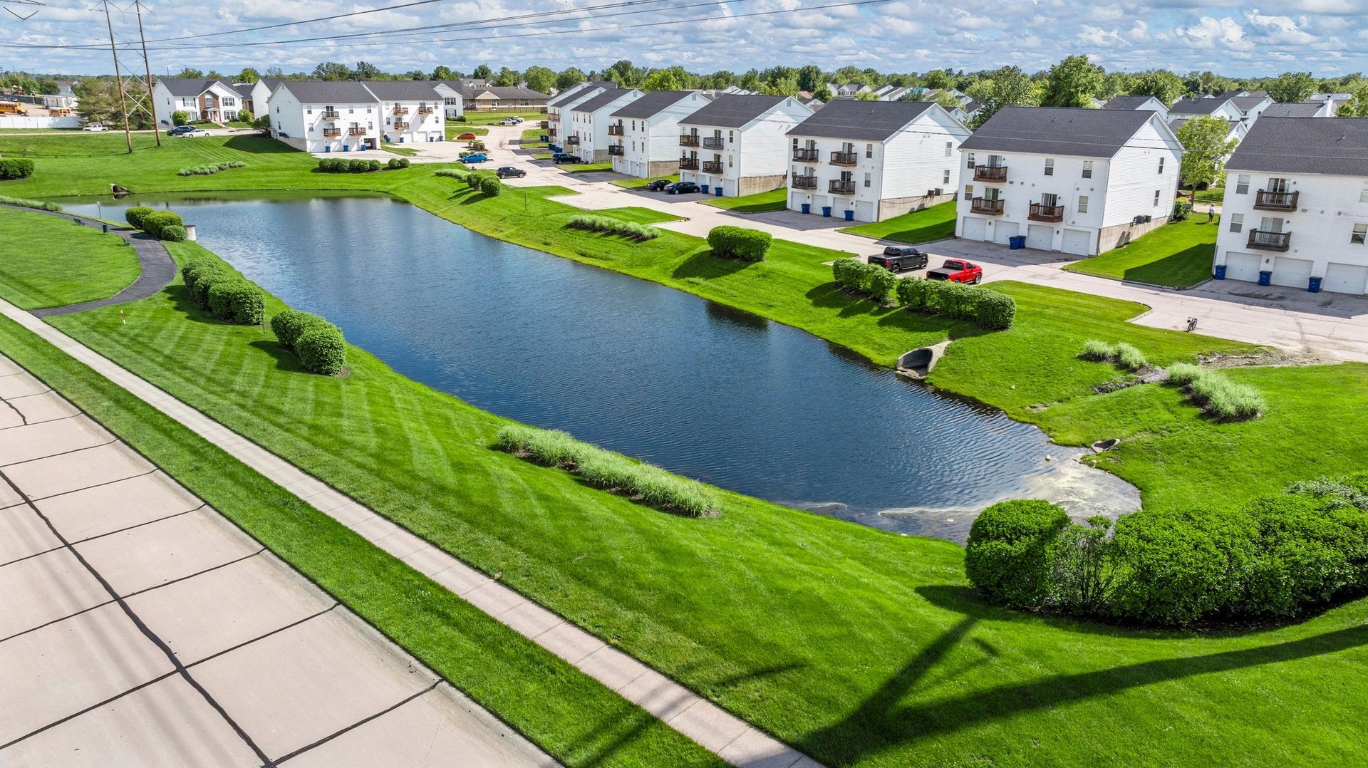 An aerial view of a residential area with a pond in the middle of it.