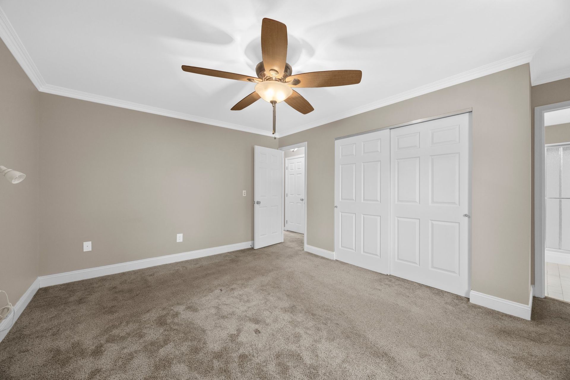An empty bedroom with a ceiling fan and a closet.