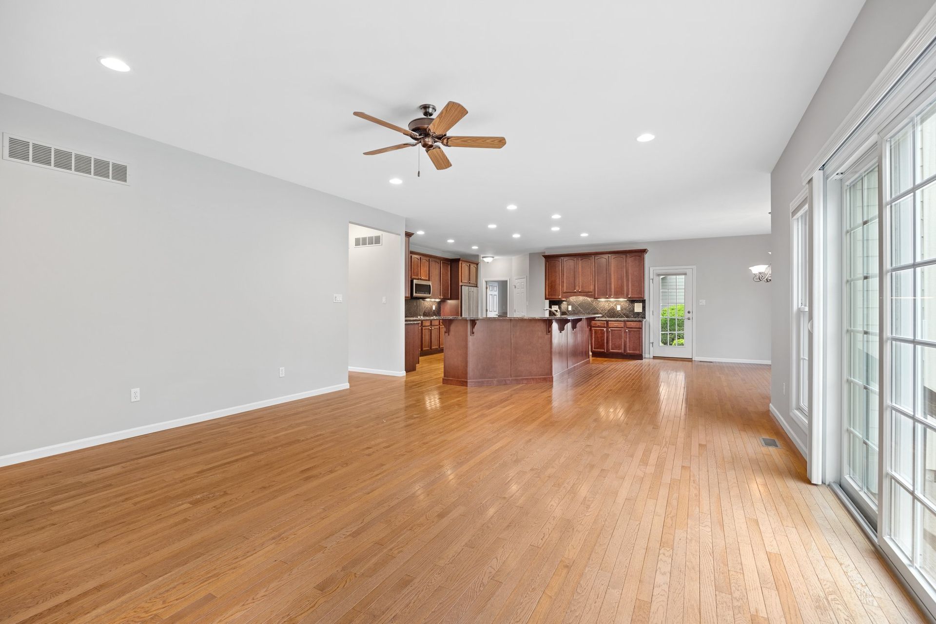 An empty living room with hardwood floors and a ceiling fan.