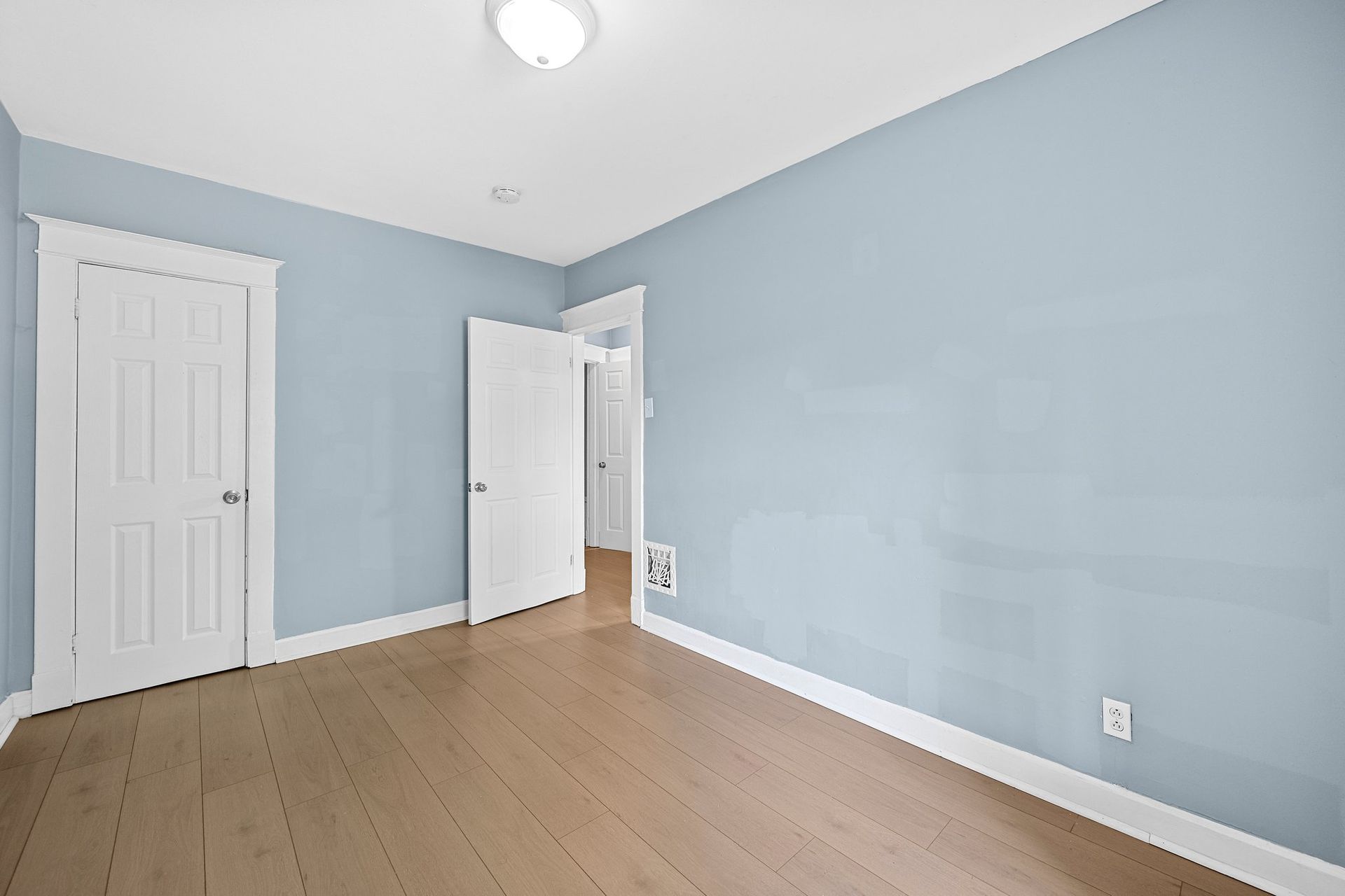 An empty bedroom with blue walls and white doors.