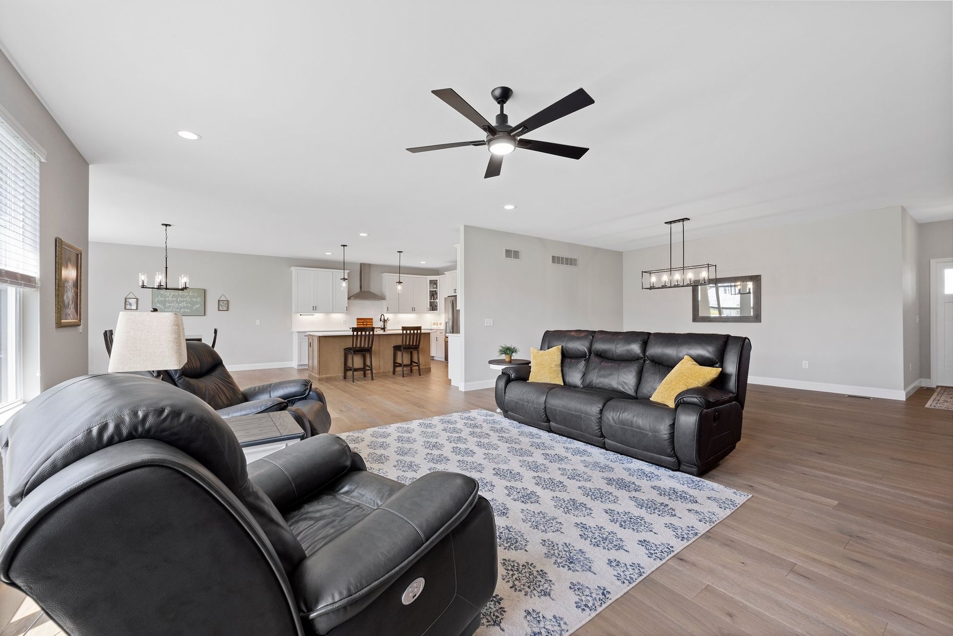 A living room with a couch , chairs , and a ceiling fan.