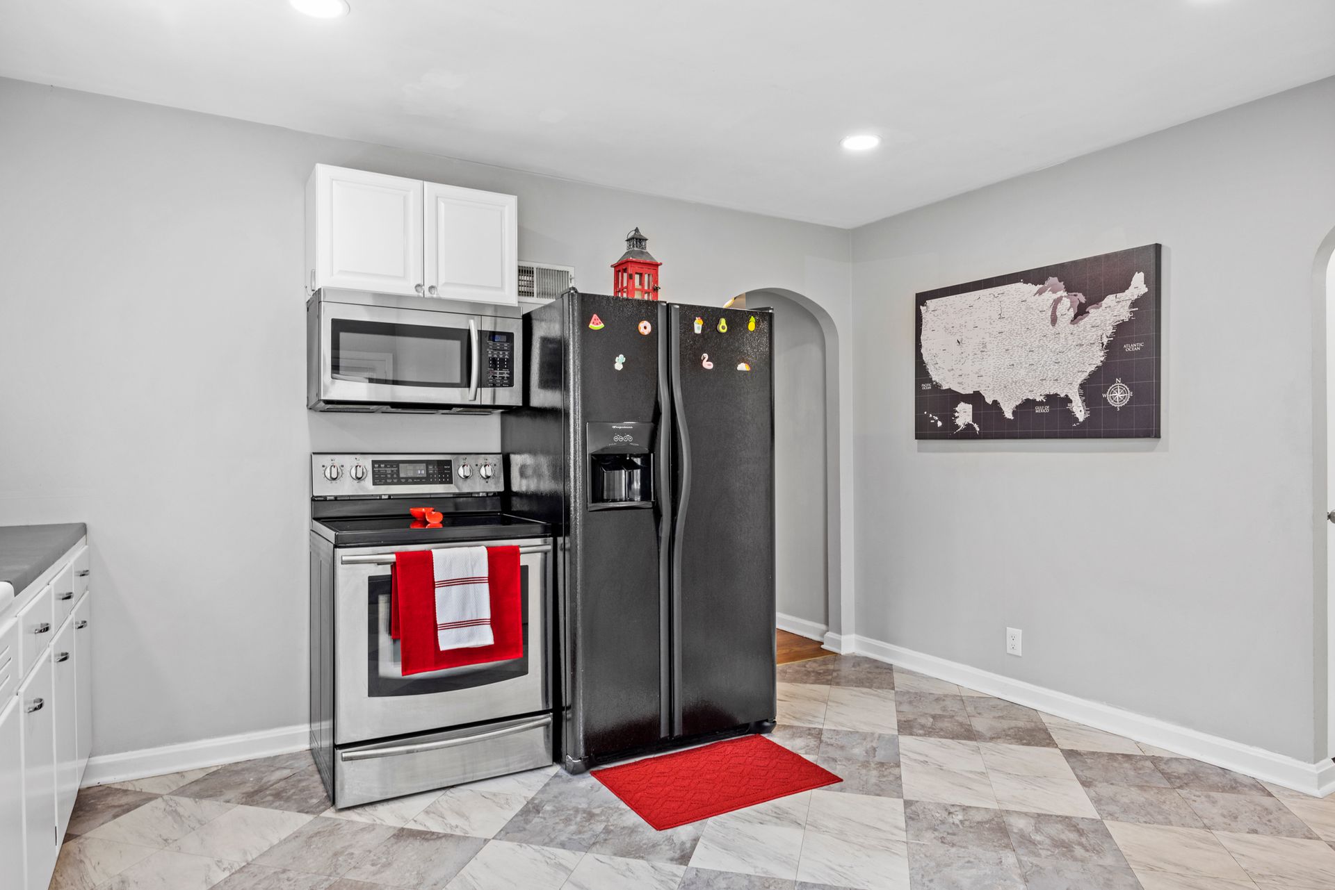 A kitchen with a black refrigerator , stove and microwave.