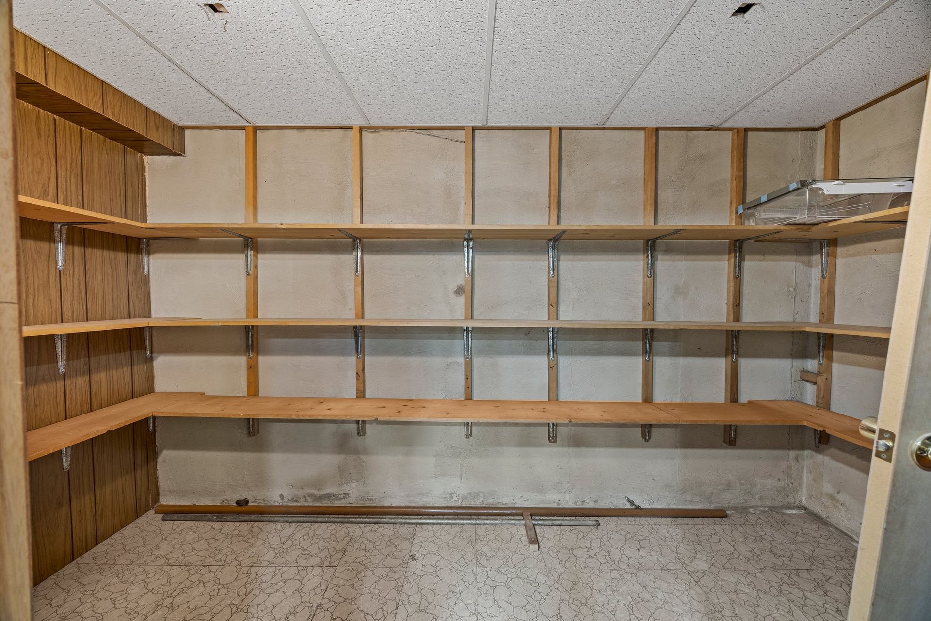 An empty room with wooden shelves and a door