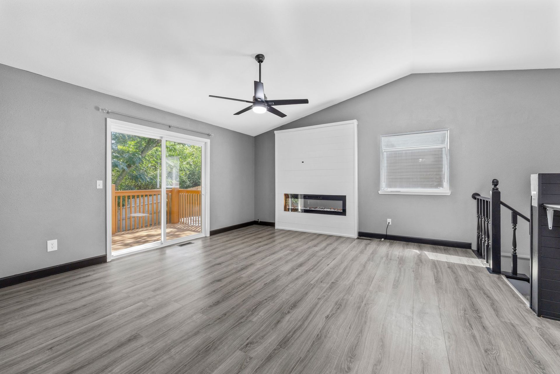 An empty living room with hardwood floors and a ceiling fan.