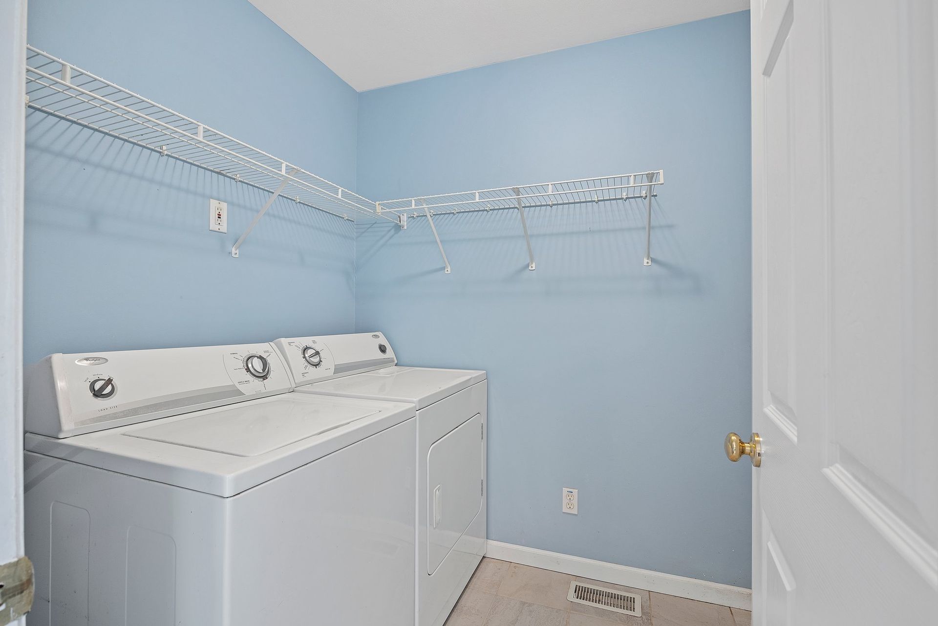 A laundry room with a washer and dryer and blue walls.