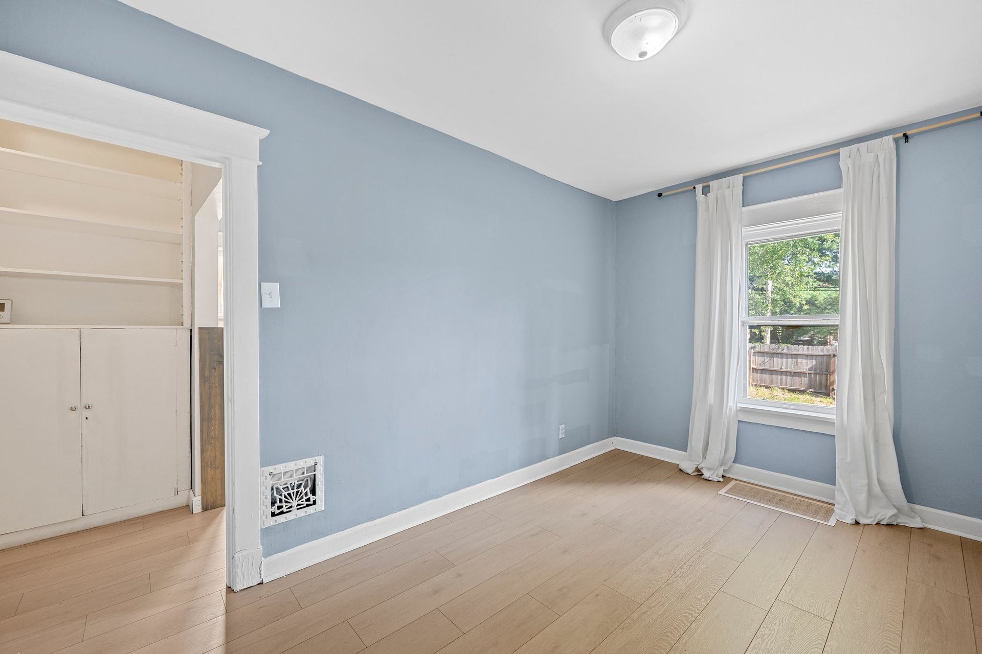 An empty room with blue walls and a window.