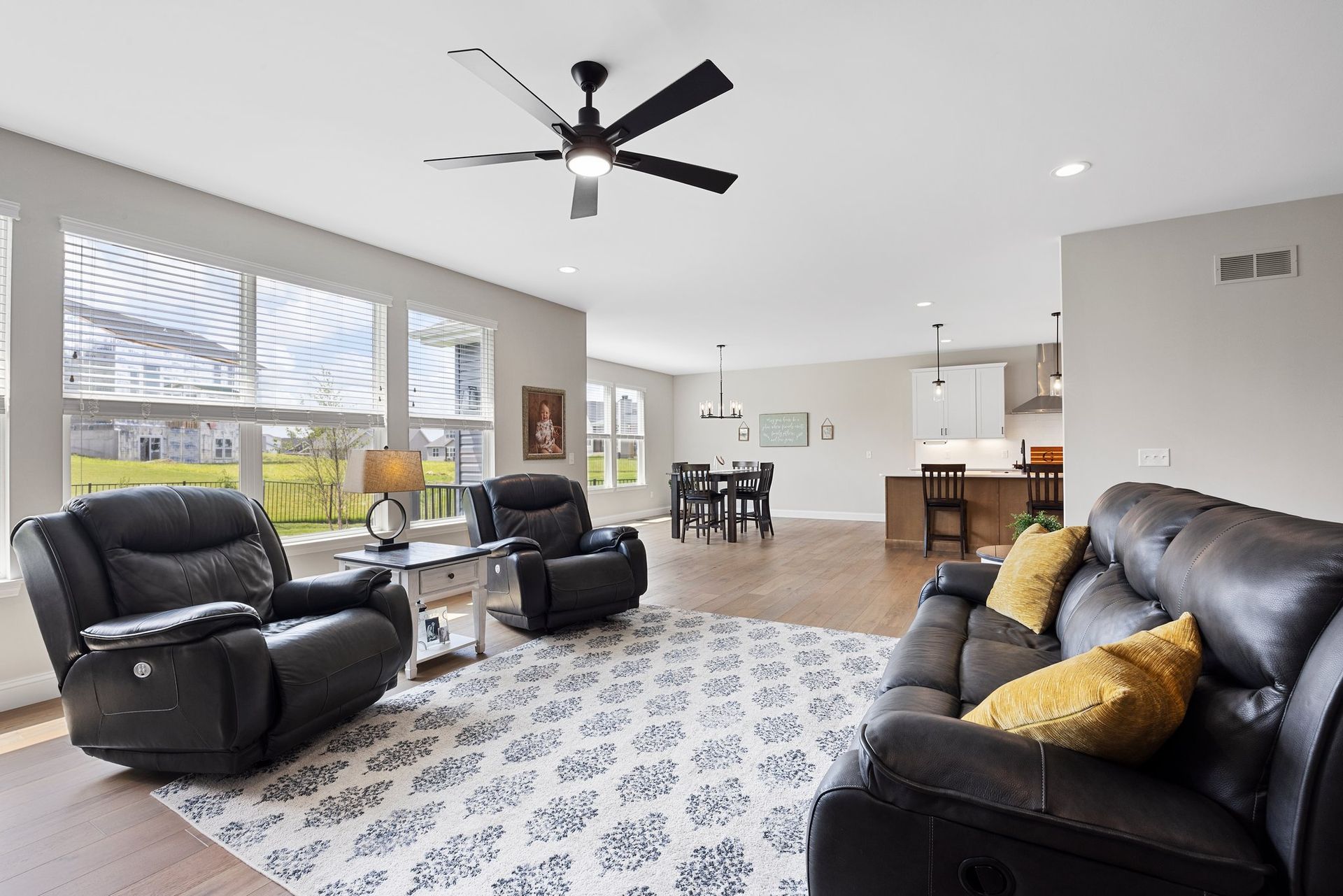 A living room with a couch and two chairs and a ceiling fan