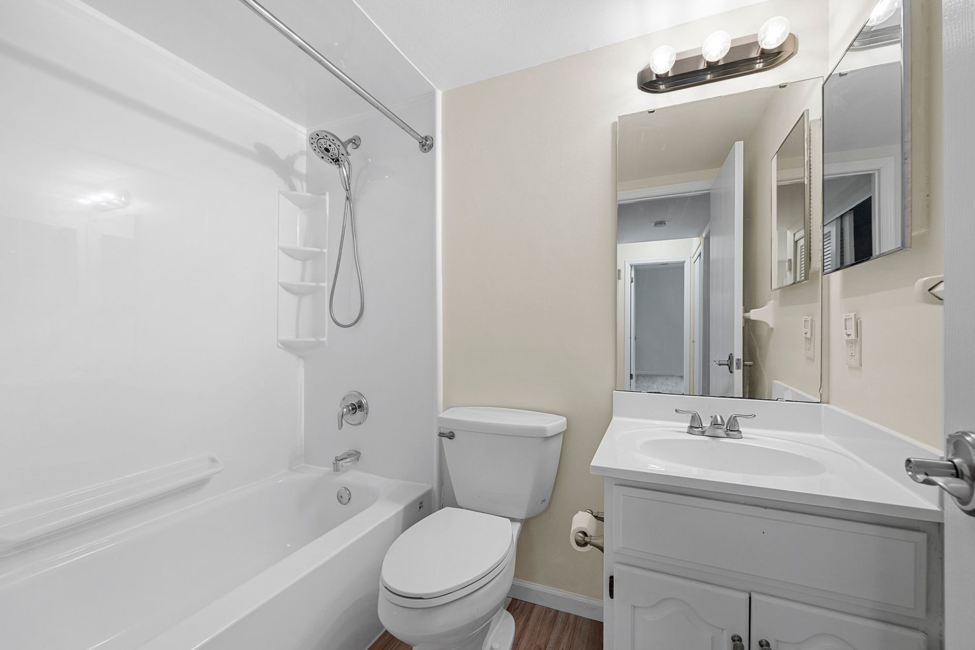 A bathroom with a toilet , sink , bathtub and mirror.
